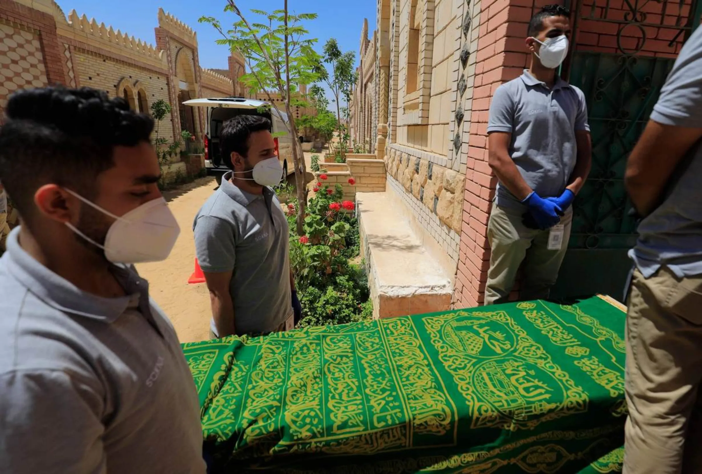 SOKNA team carry a coffin draped in a green prayer cloth into a funeral ceremony in Cairo, Egypt. May 19, 2021. Thomson Reuters Foundation/SOKNA