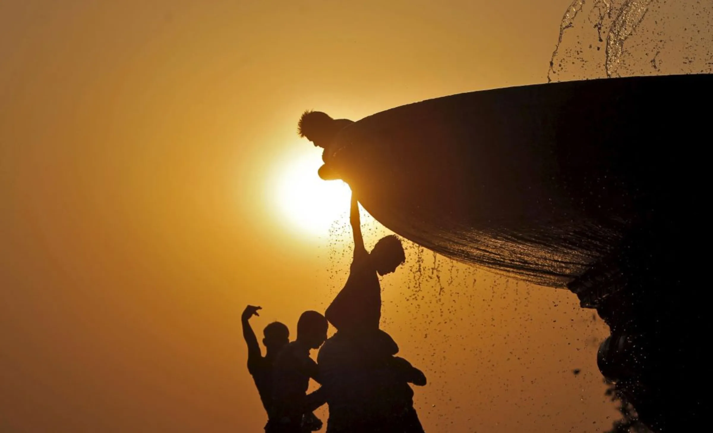 Boys cool off under a water fountain on a hot summer evening in New Delhi, India, April 25, 2016