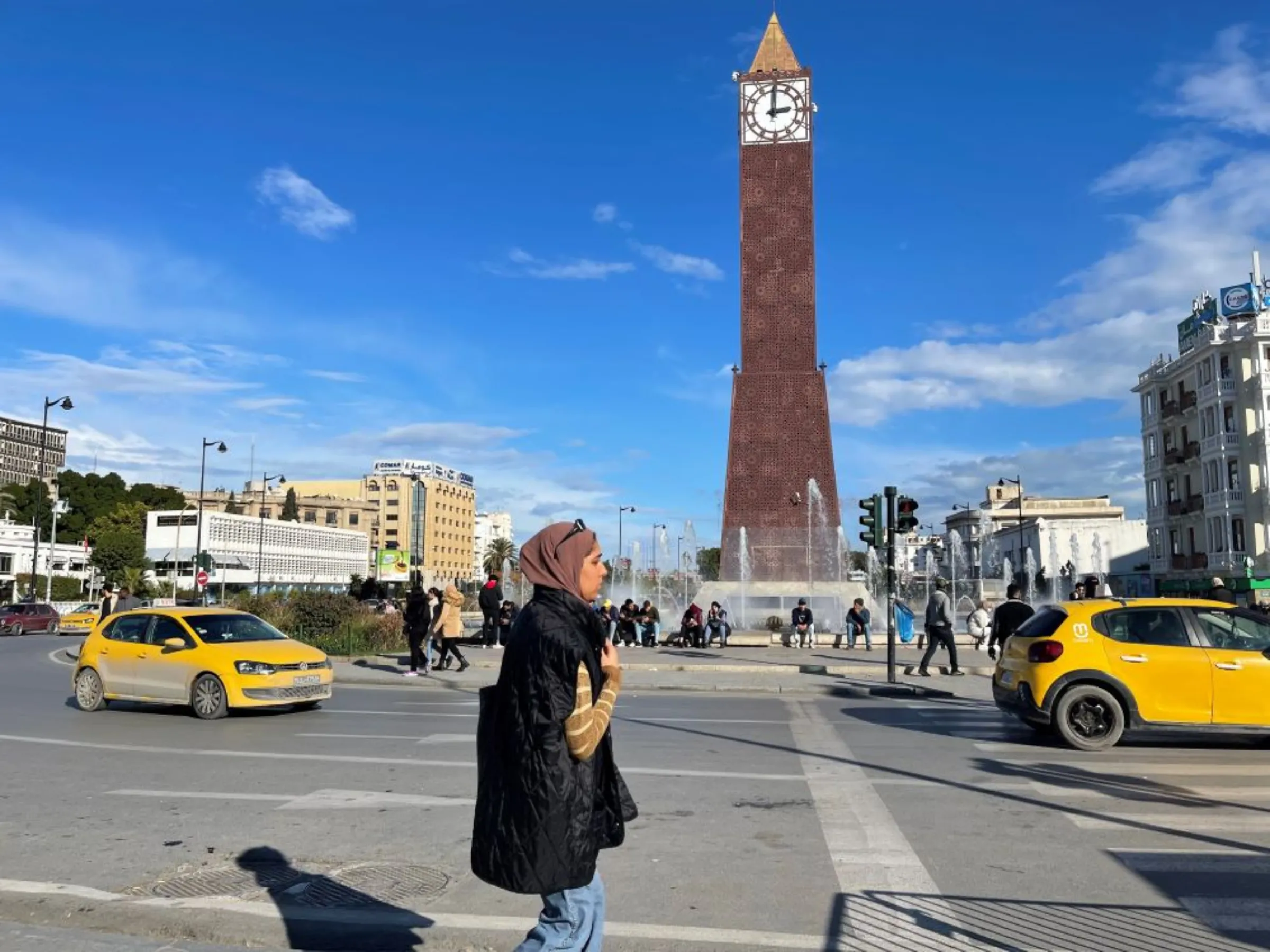 A woman walks past Avenue Habib Bourguiba Clocktower in central Tunis on January 29, 2023