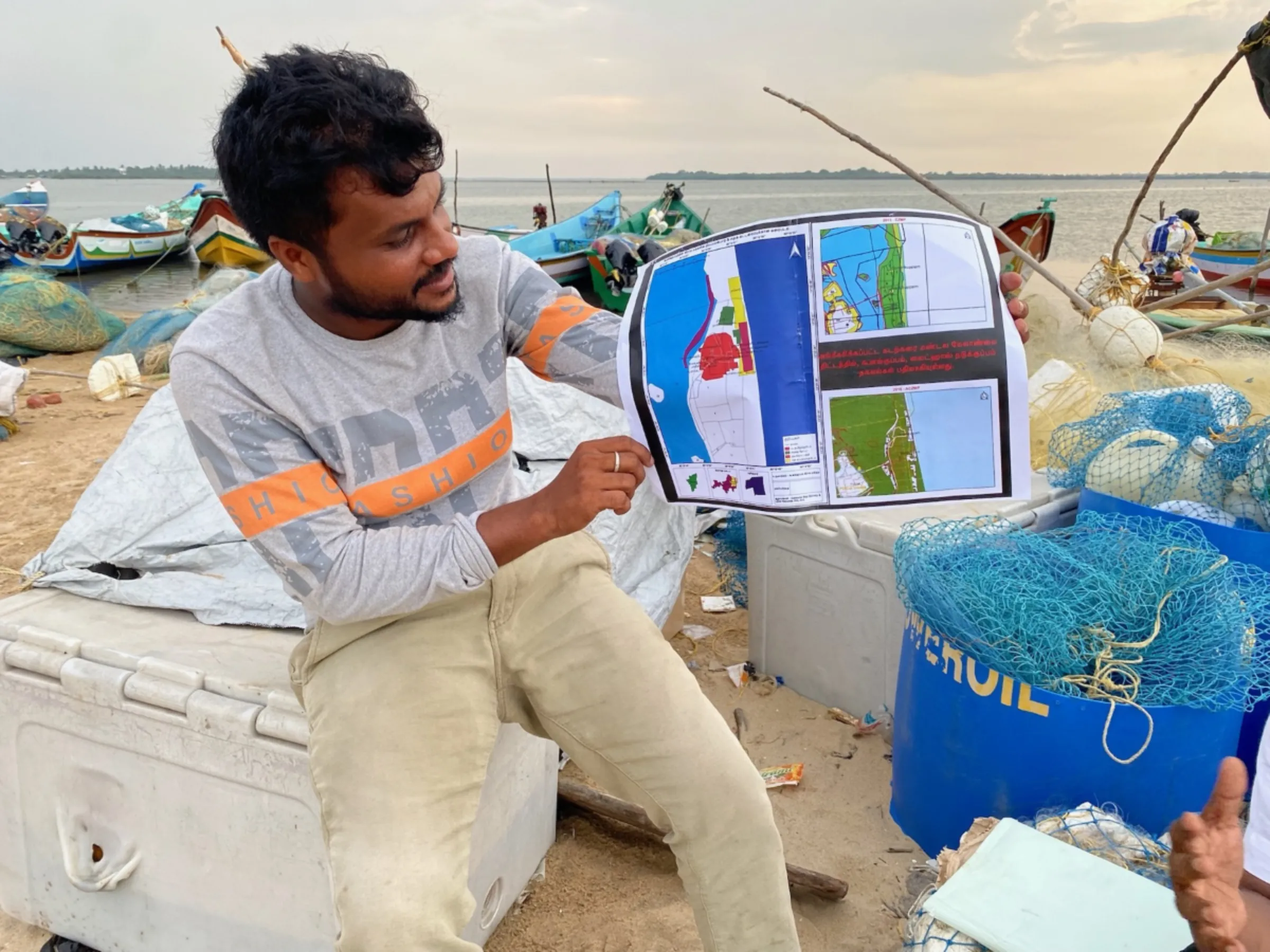 Bharath S Raji poses with a printed map created by fishermen volunteers in Gunankuppam, near Chennai, India July 14, 2023