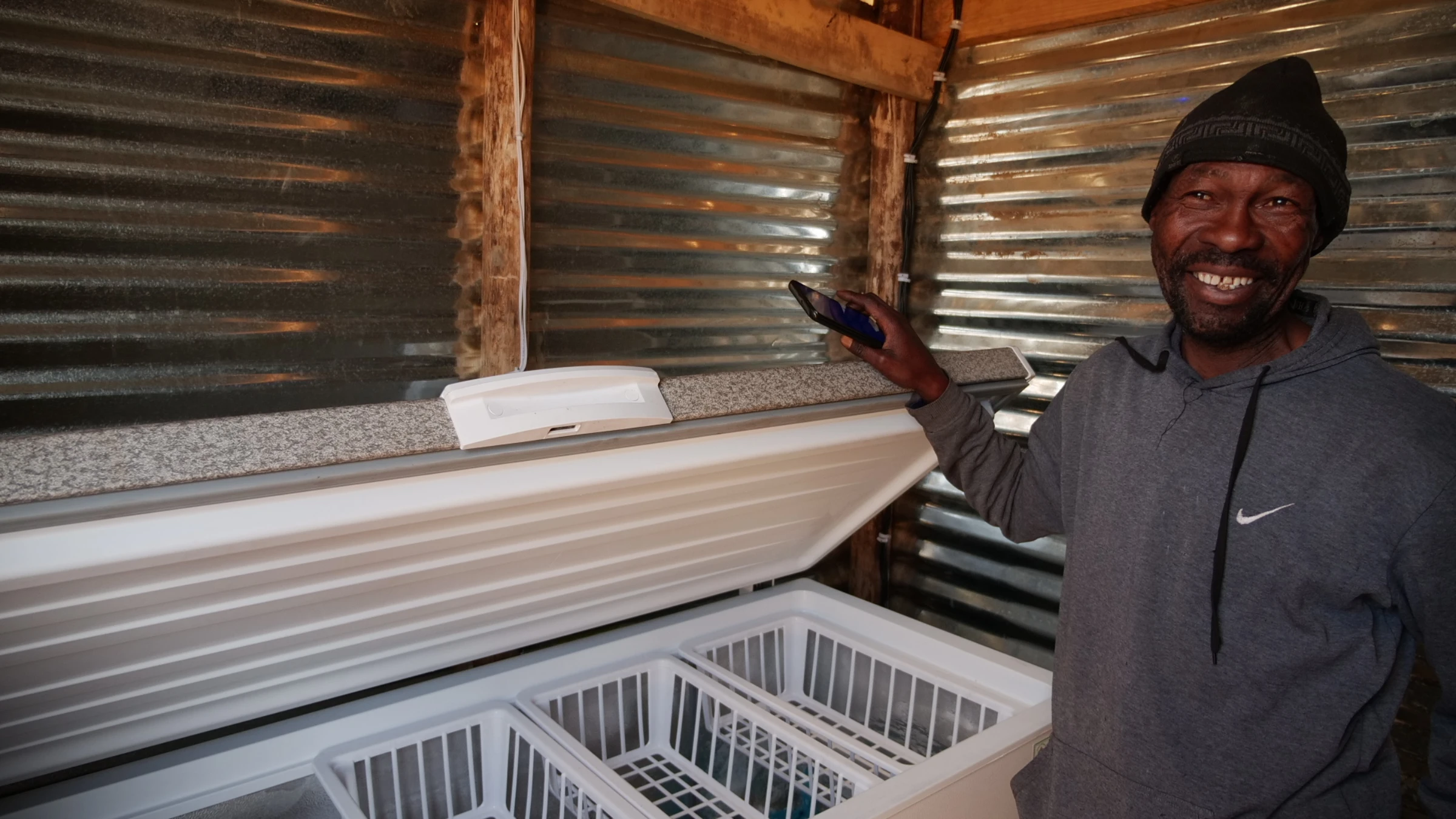 Slomo Mngomezulu smiles as he opens up one of the solar-powered community chest freezers that he oversees in Ermelo, South Africa, July 9, 2025. Thomson Reuters Foundation/Kim Harrisberg