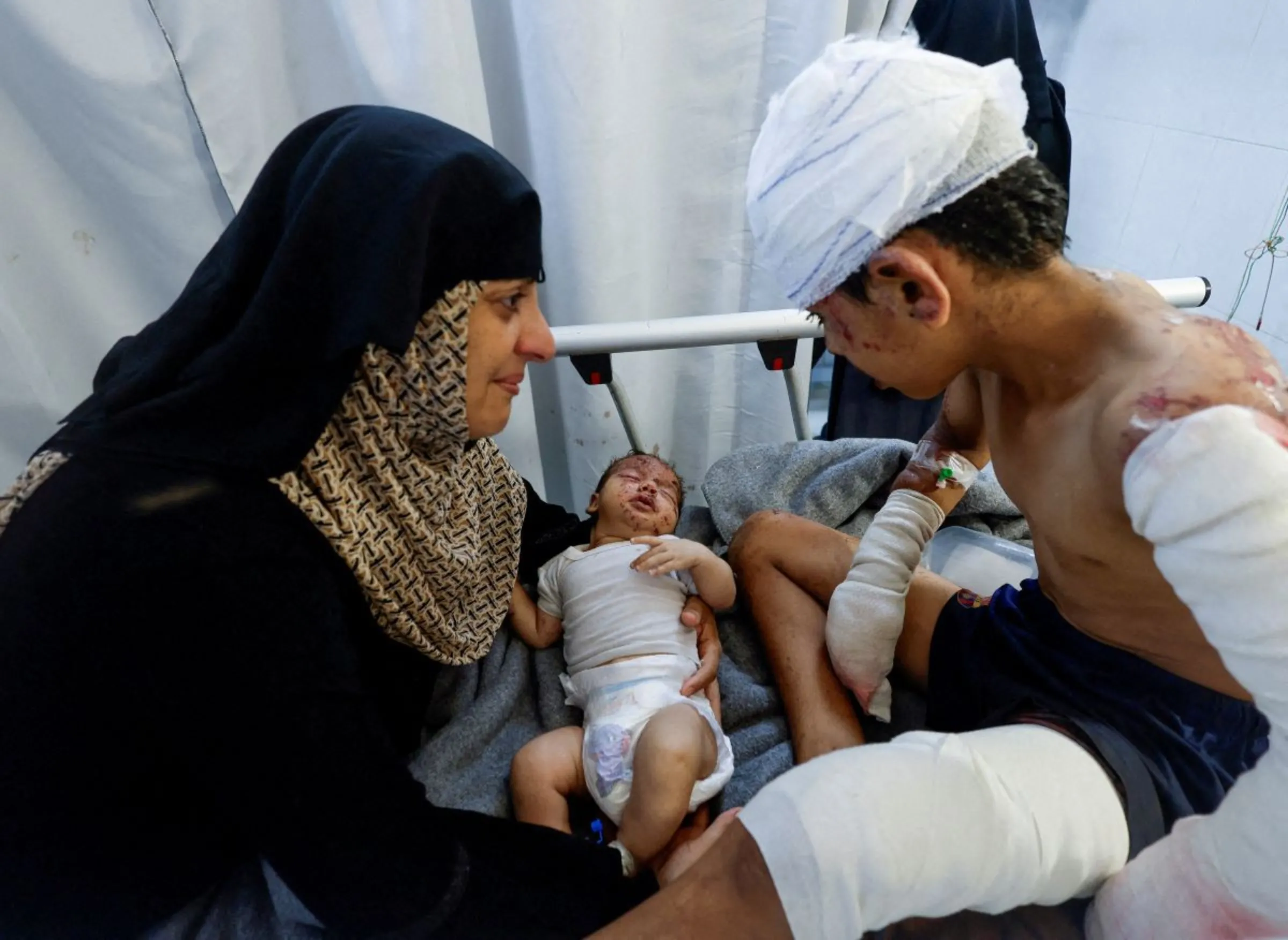 A wounded Palestinian child and his brother rests on a bed, at Nasser hospital, amid Israel-Hamas conflict, in Khan Younis in the southern Gaza Strip July 2, 2024. REUTERS/Mohammed Salem