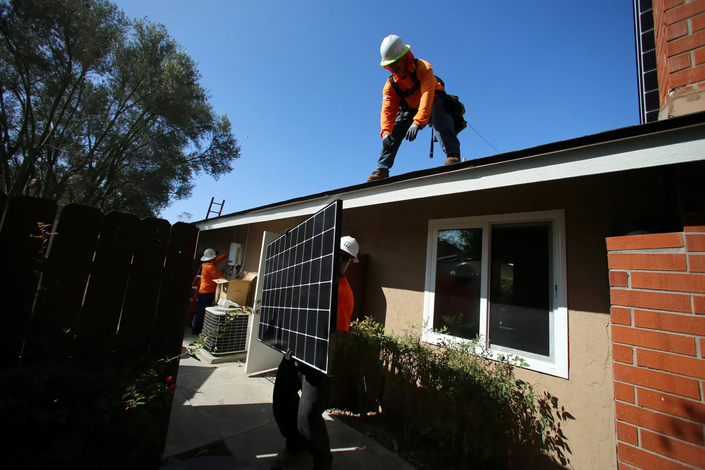 Workers lift a solar panel onto a roof during a residential solar installation in Scripps Ranch, San Diego, California, U.S. October 14, 2016. REUTERS/Mike Blake