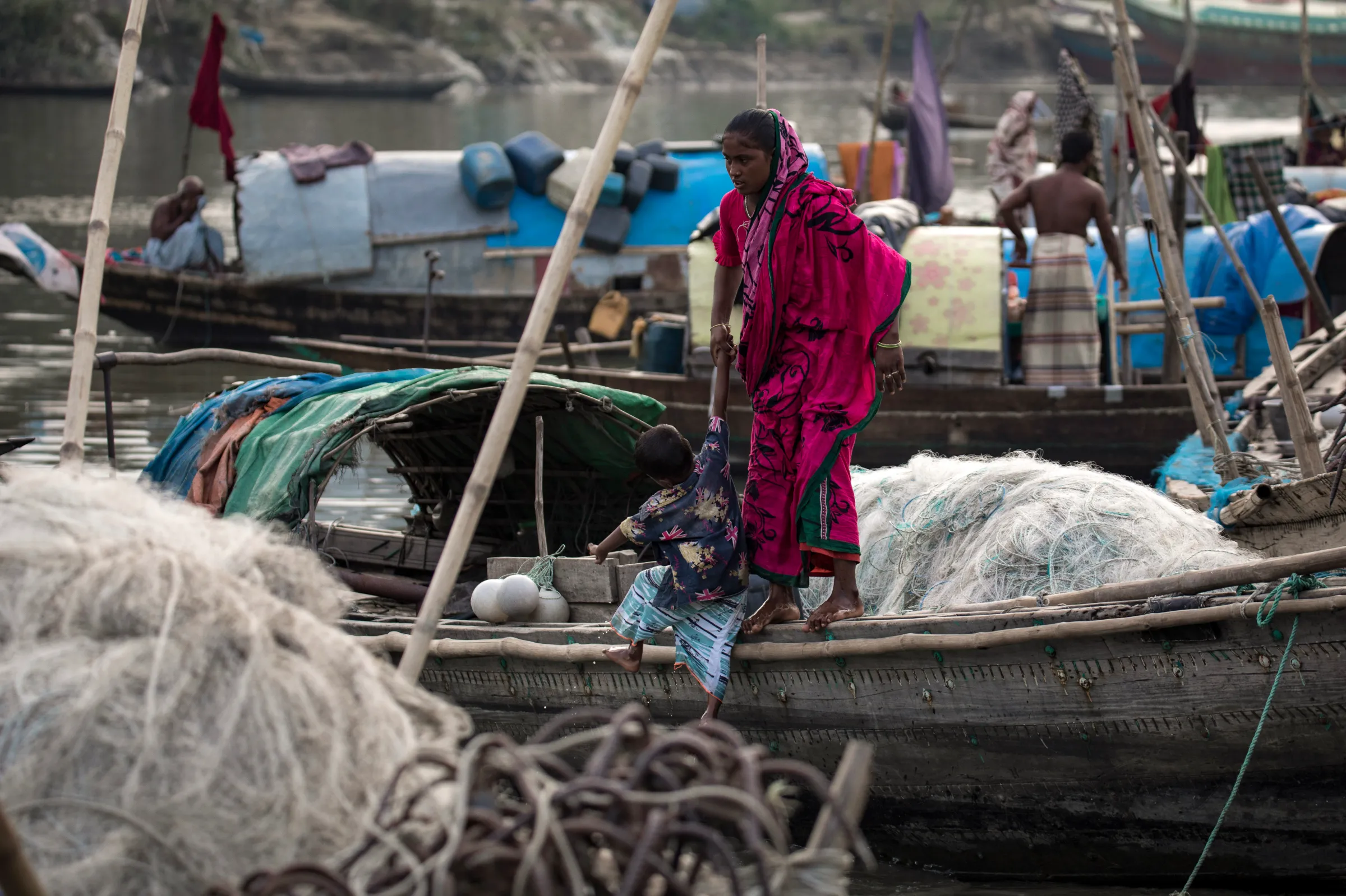 A woman pulls a child on to the side of a boat