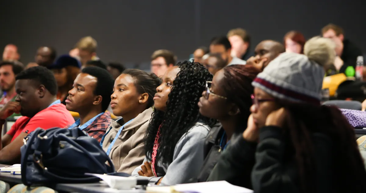 Attendees of the Deep Learning Indaba listen to a speaker in a lecture hall at Stellenbosch University, South Africa.