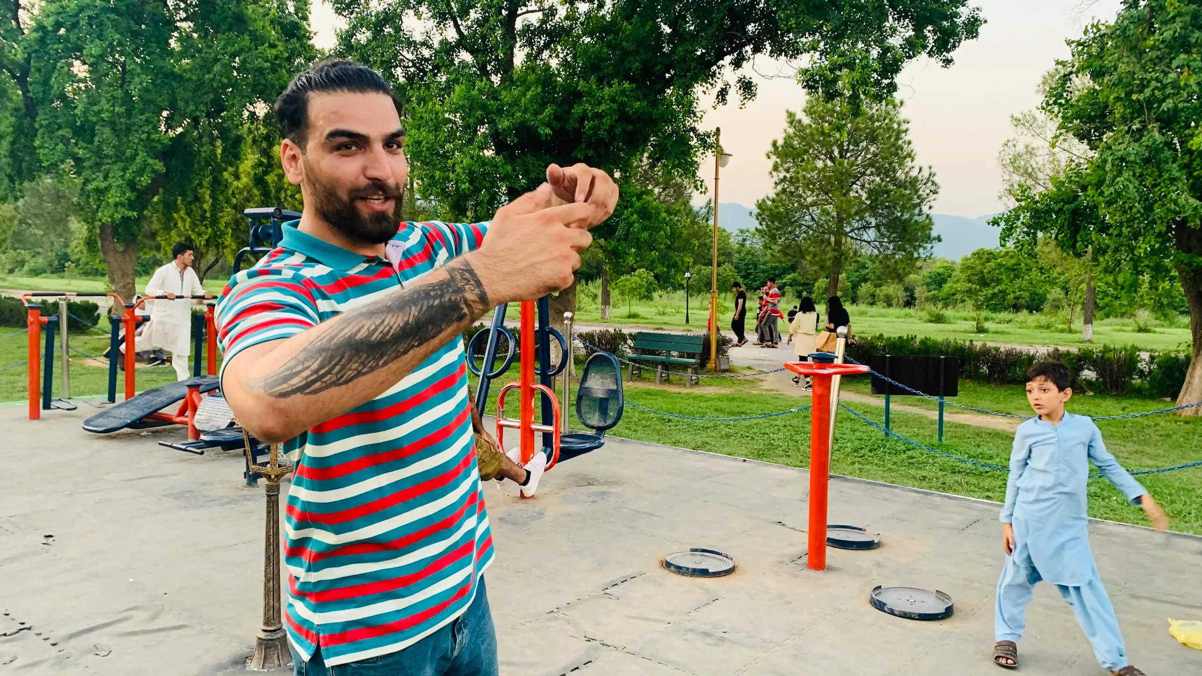 A man demonstrates a judo throw with his hands while standing in a park in Pakistan