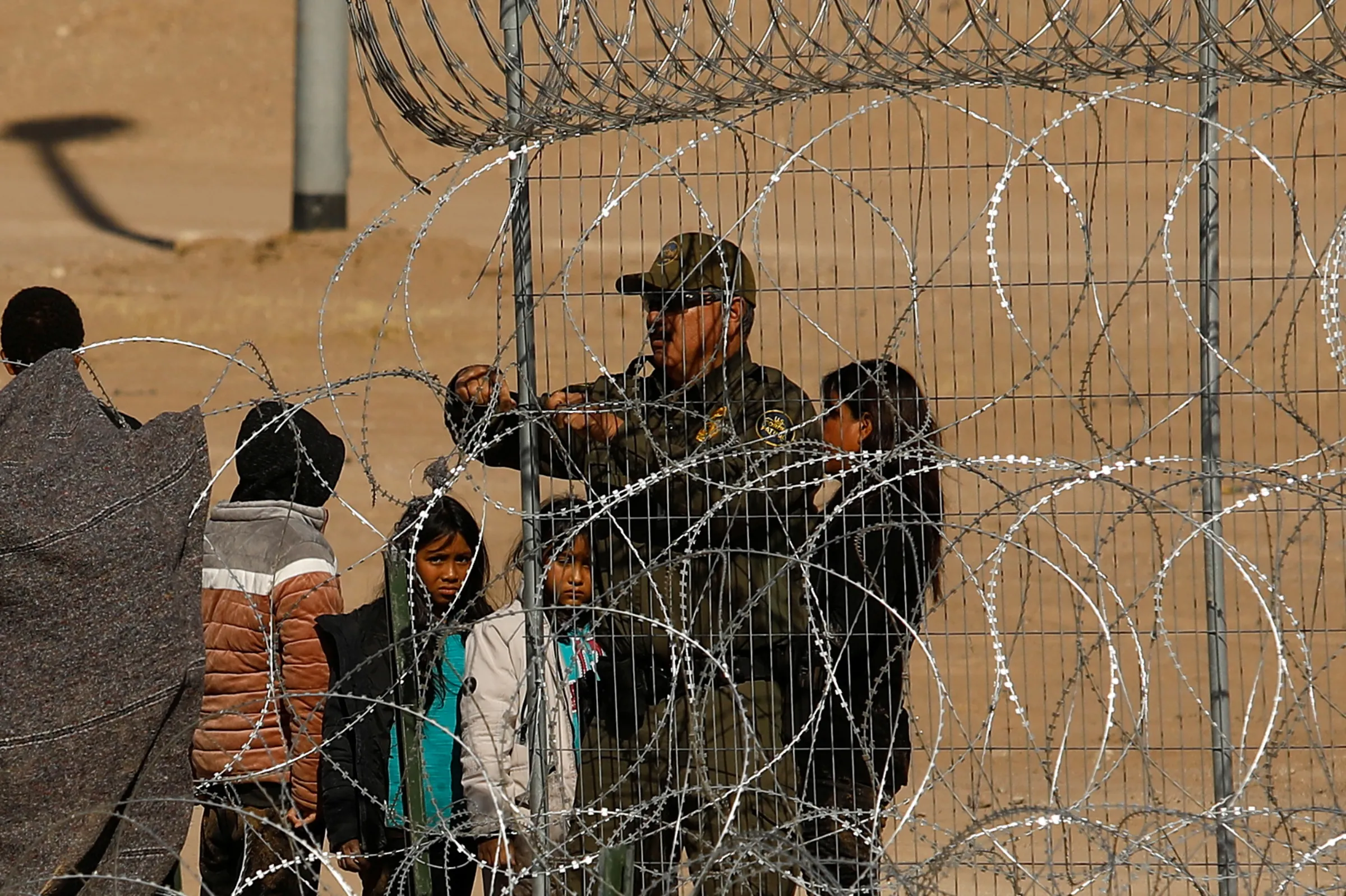 A U.S. Border Patrol agent stands next to migrants seeking asylum before being returned to Mexico from the United States after U.S. authorities prevented their crossing, as seen from Ciudad Juarez, Mexico January 22, 2024. REUTERS/Jose Luis Gonzalez