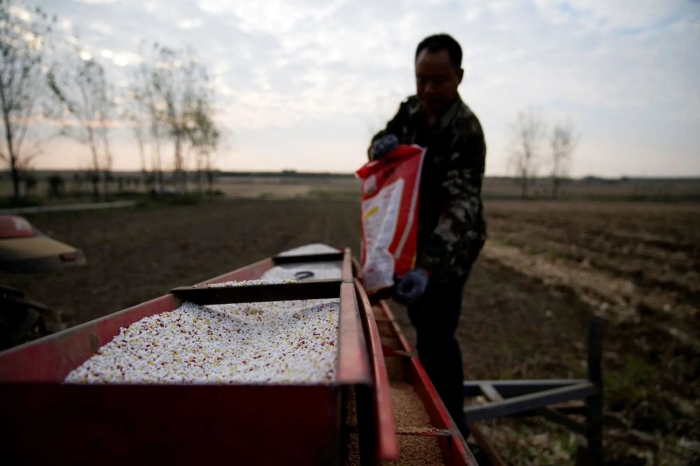 A farmer loads seeds into a seeder with fertiliser, on a wheat field in Nanyang, Henan province, China October 13, 2021