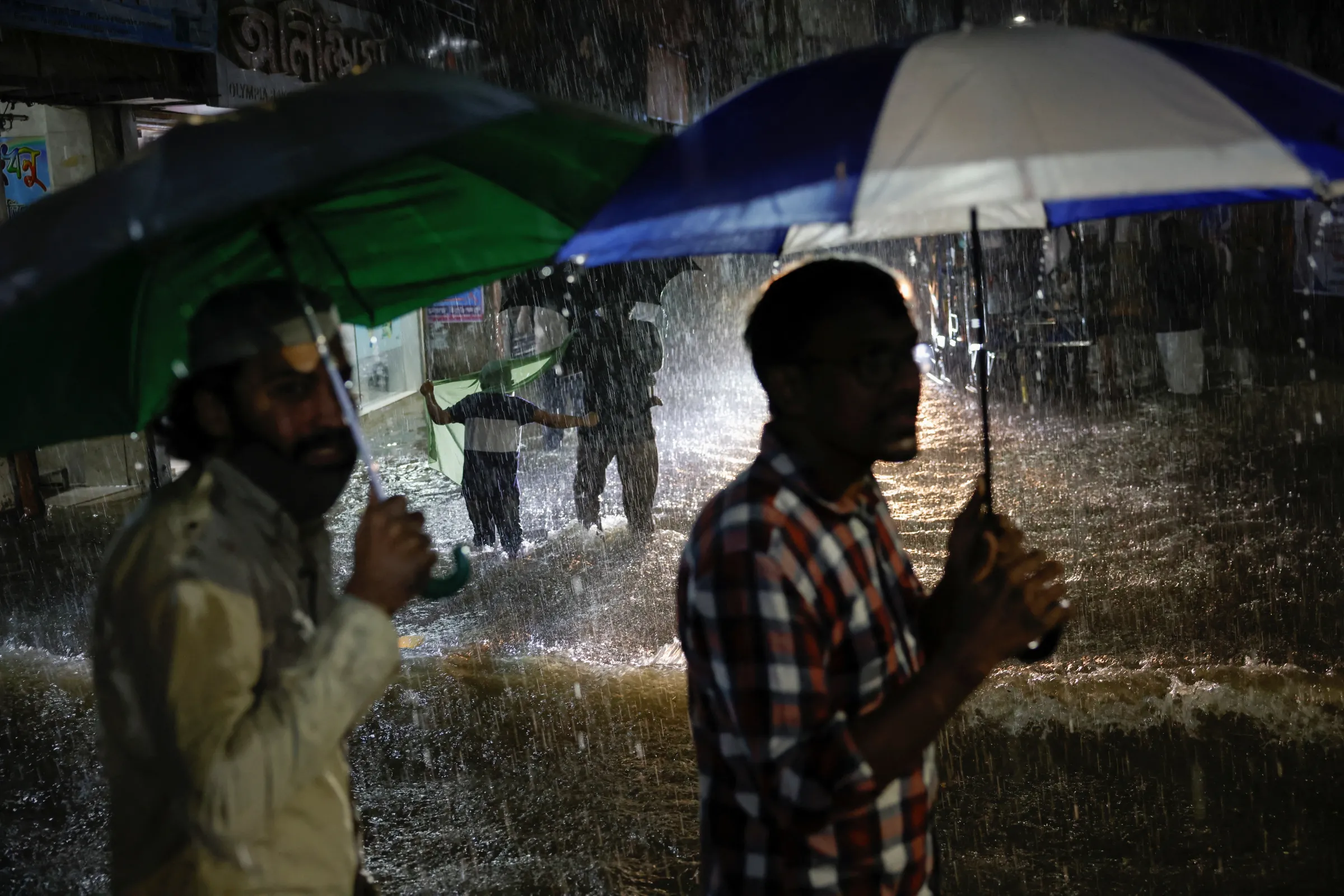 People wade through a flooded street amid continuous rain before the Cyclone Sitrang hits the country in Dhaka, Bangladesh, October 24, 2022. REUTERS/Mohammad Ponir Hossain