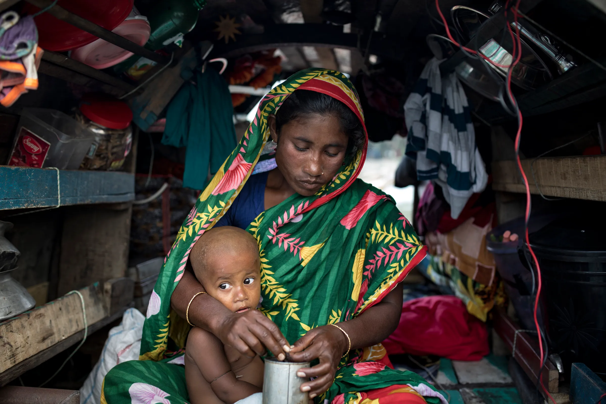 A woman cradles a baby as they sit on a boat where they live