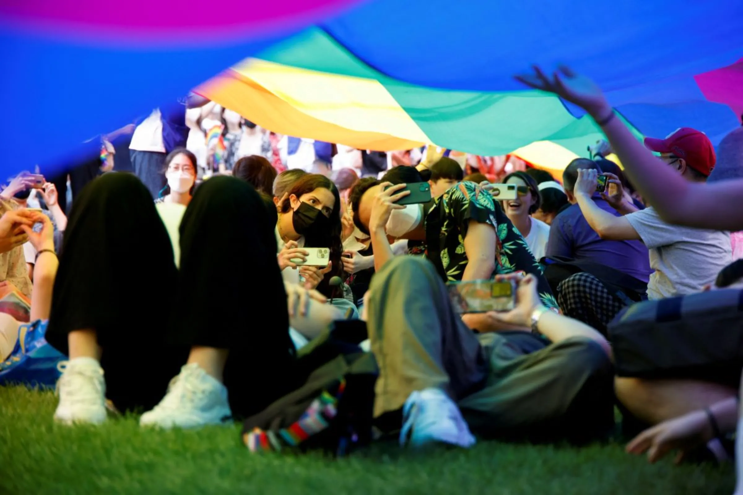 Participants take pictures under the rainbow flag during the Korea Queer Culture Festival 2022 in central Seoul, South Korea, July 16, 2022. REUTERS/Heo Ran