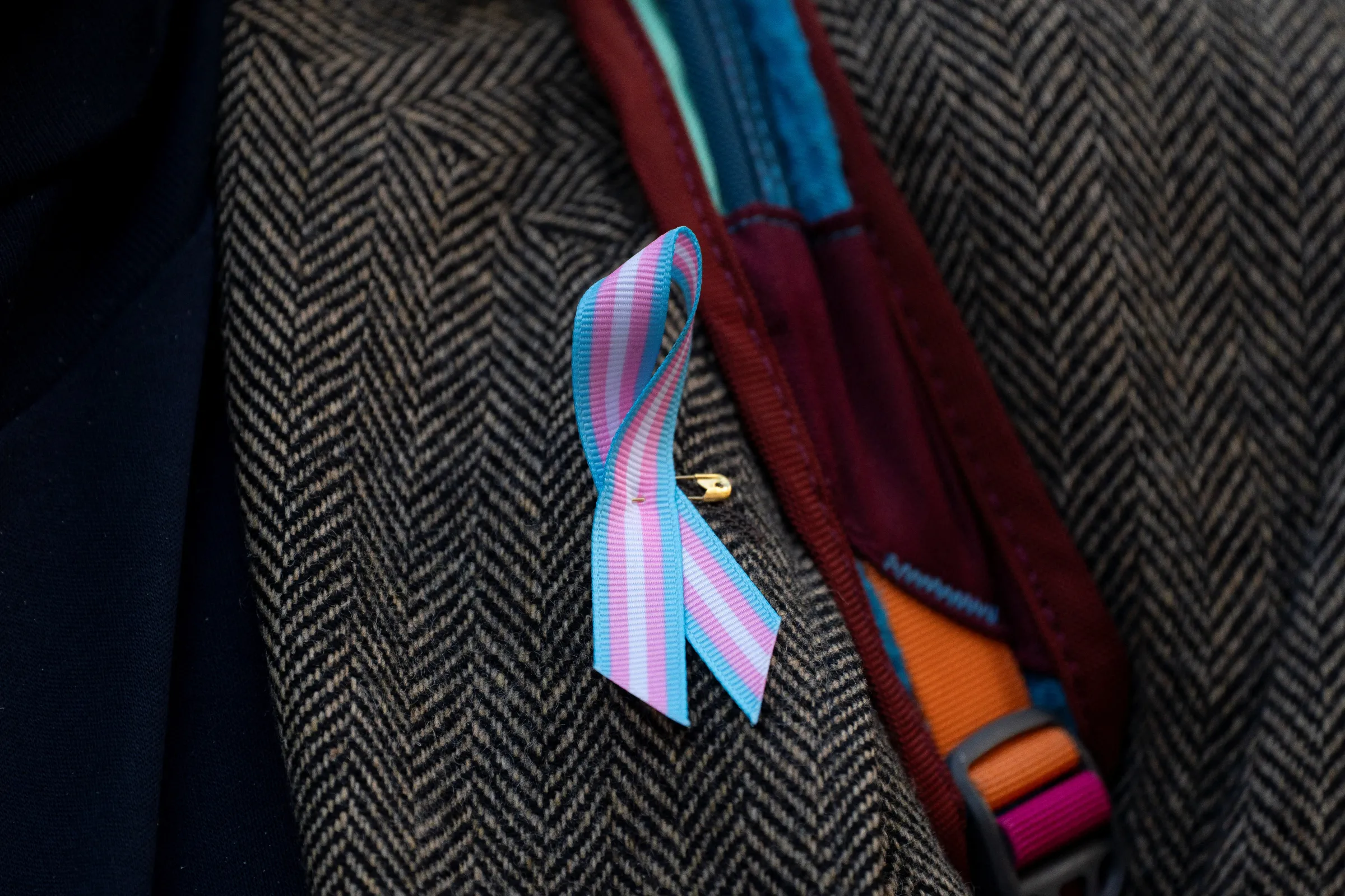 A supporter wears a pro-trans ribbon after a hearing in the multi-state lawsuit over President Trump's order ending all federal funding or support for healthcare that aids gender transitions for people younger than 19, outside a courthouse in Seattle, Washington, U.S., February 28, 2025. REUTERS/David Ryder