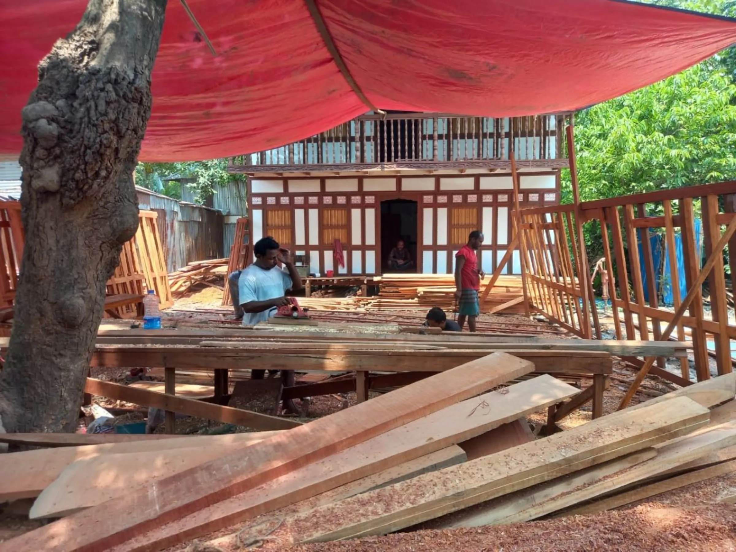 Workers make wooden houses in the yard of Faysal Rahman's manufactory in Munshiganj that are said to last for 30 to 80 years, May 31, 2023