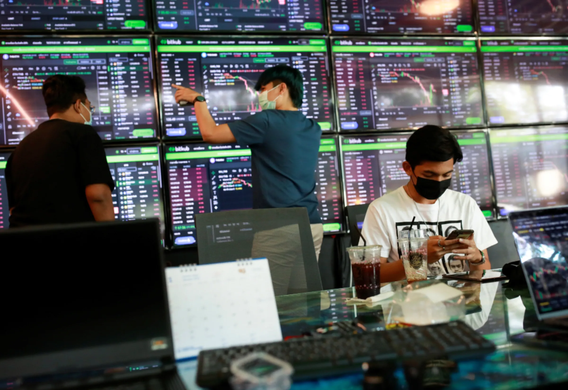 People pass their time at a cafe which has dozens of screens showing the latest trends and prices on various cryptocurrencies for their crypto investors' customers in Nakhon Ratchasima, Thailand, January 21, 2022