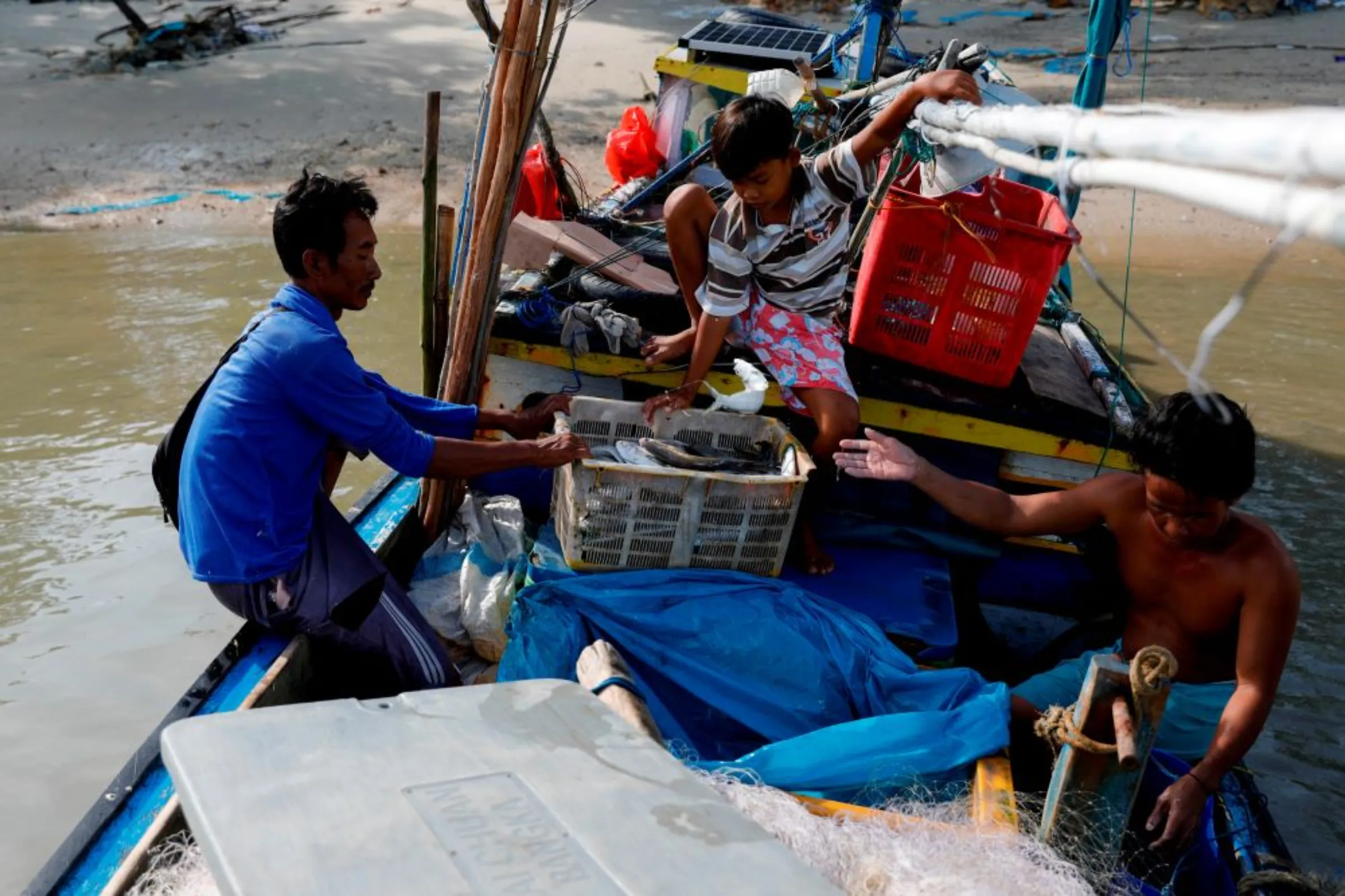 A local fisherman, his son Avanza, and his friend, collect their catches as they return from fishing, in Batu Perahu village, in Toboali, on the southern shores of the island of Bangka, Indonesia, May 2, 2021