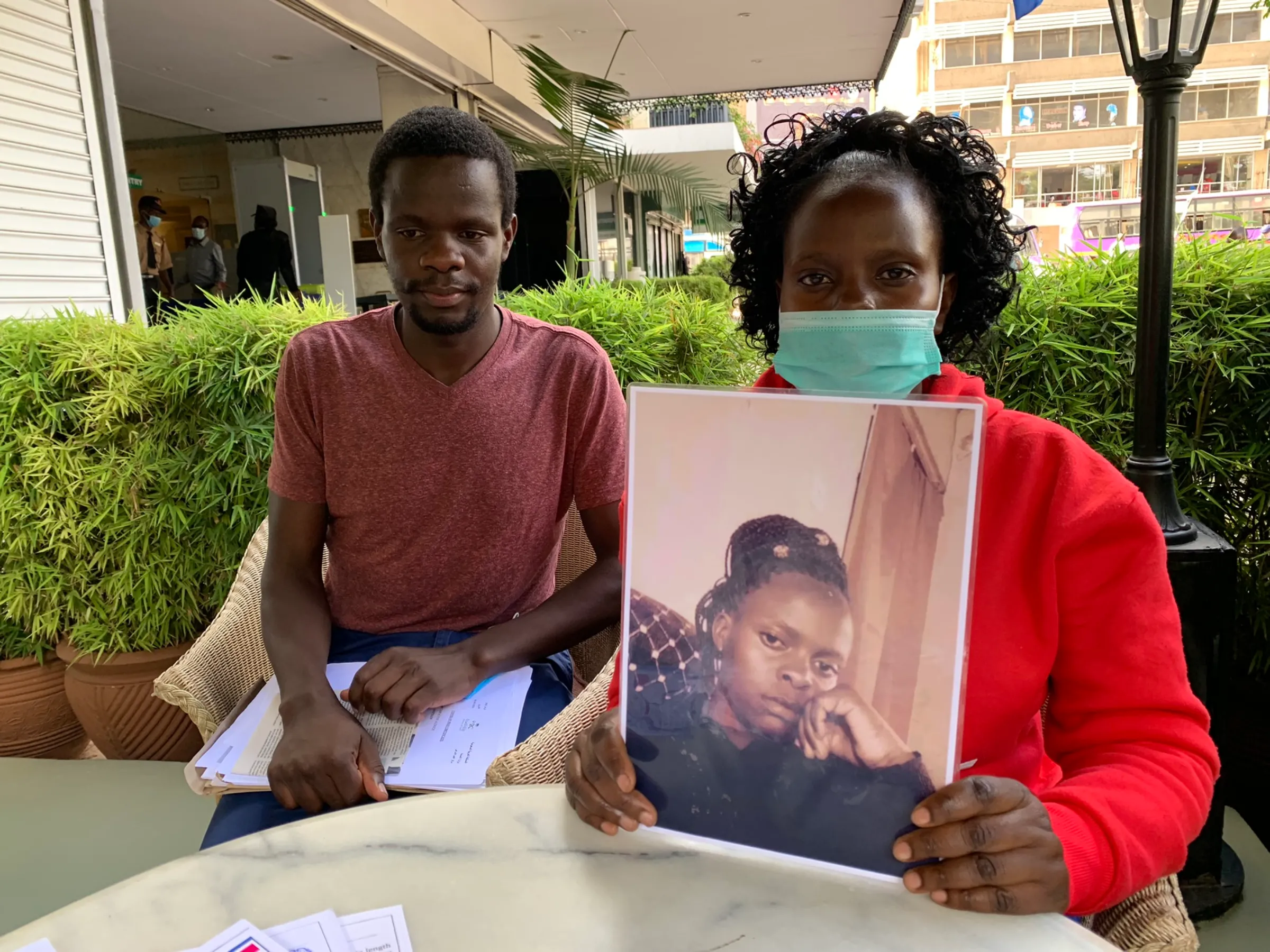 Beryl Aluoch and Stephen Aluoch pose with a picture of their sister Caroline Aluoch who died while working as a maid in Saudi Arabia