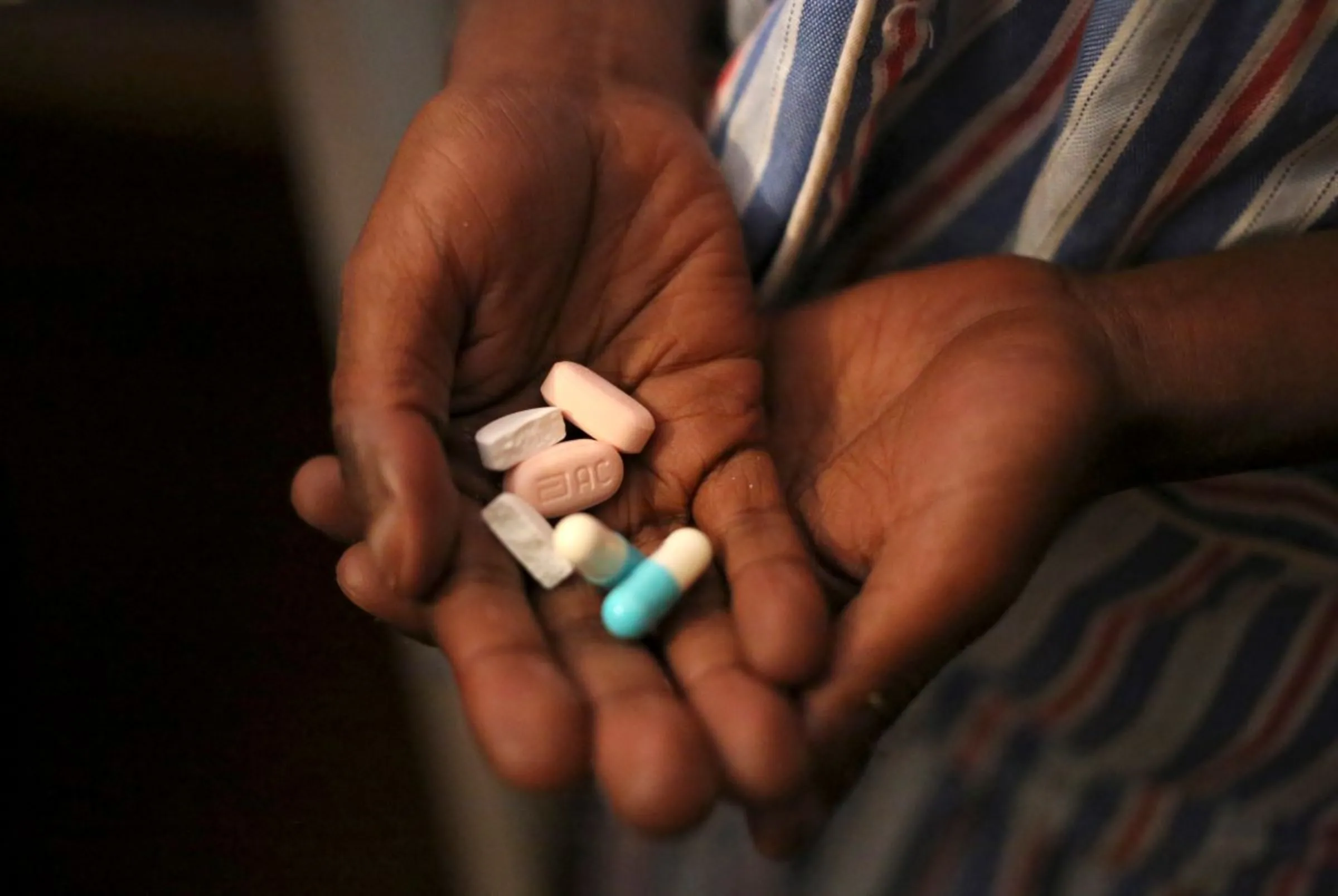 Nine-year-old Tumelo shows off antiretroviral (ARV) pills before taking his medication at Nkosi's Haven, south of Johannesburg November 28, 2014. REUTERS/Siphiwe Sibeko