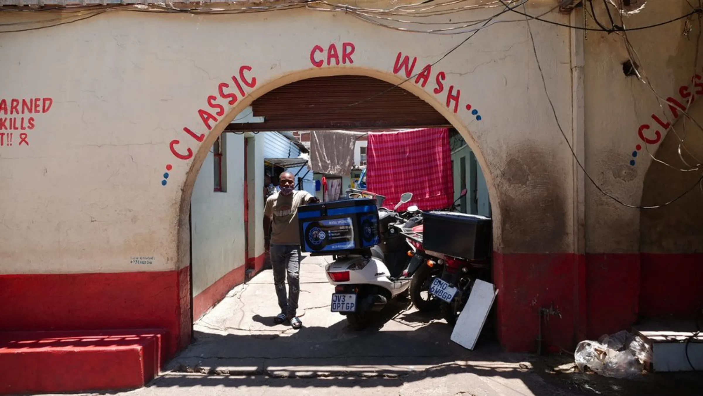 A driver poses alongside a row of food delivery motorcycles in Johannesburg, South Africa. March 22, 2021. Thomson Reuters Foundation/Kim Harrisberg