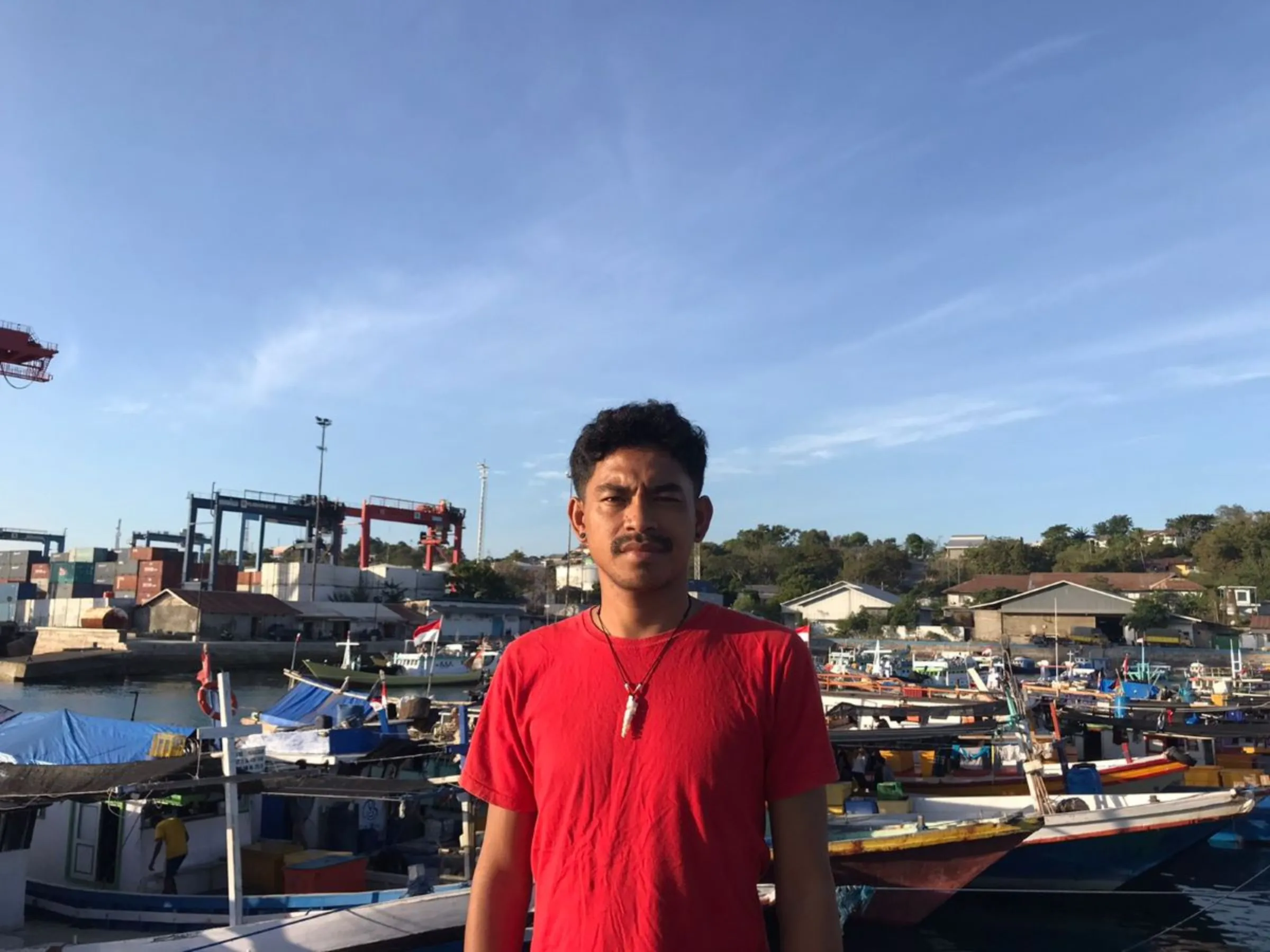 Fisherman and free diver Radith Giantiano poses by boats in a port in Kupang, East Nusa Tenggara, Indonesia in May 2023