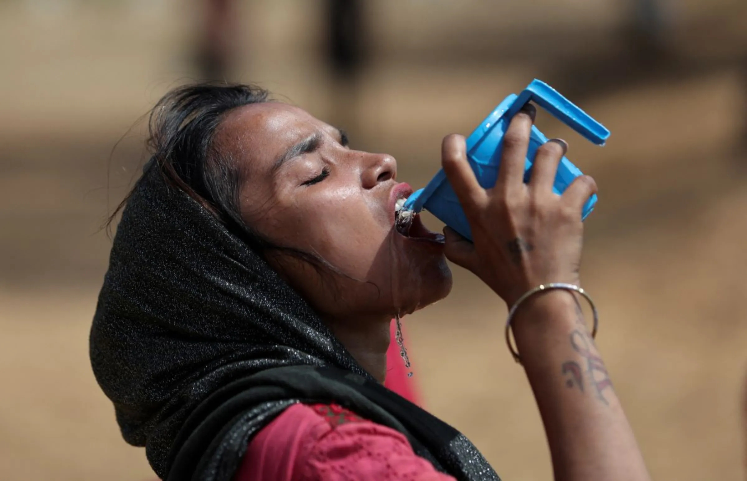 A woman drinks water from a mug on a hot summer day in New Delhi, India June 9, 2023