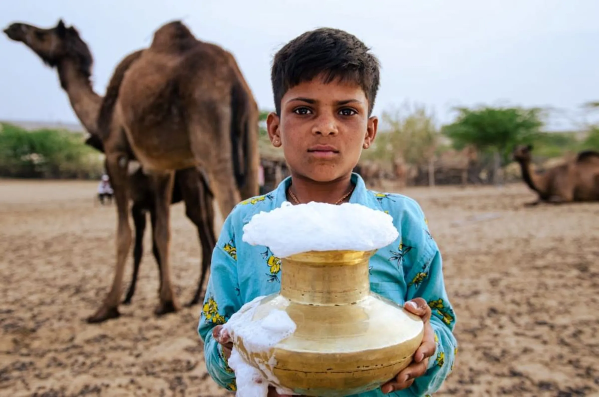 A child camel herder holds a container of fresh camel's milk in the Grandhi village of Rajasthan, India January 14, 2023. Desert Resource Centre/Handout Via Thomson Reuters Foundation