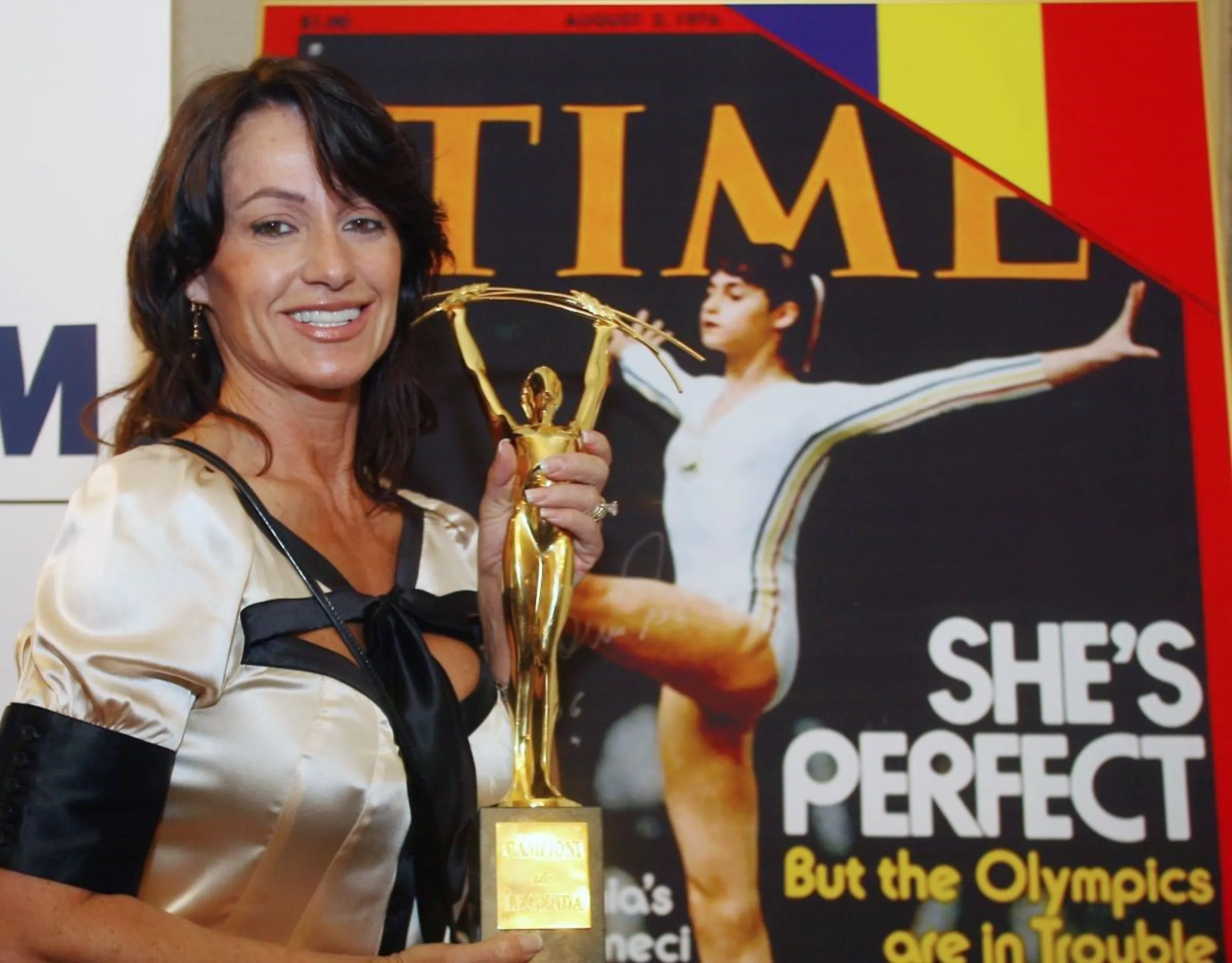 Romanian Olympic gold medal gymnast Nadia Comaneci holds the 'Legendary Champions' trophy, in front of the August 1976 Time magazine cover in Bucharest September 15, 2006. REUTERS/Bogdan Cristel