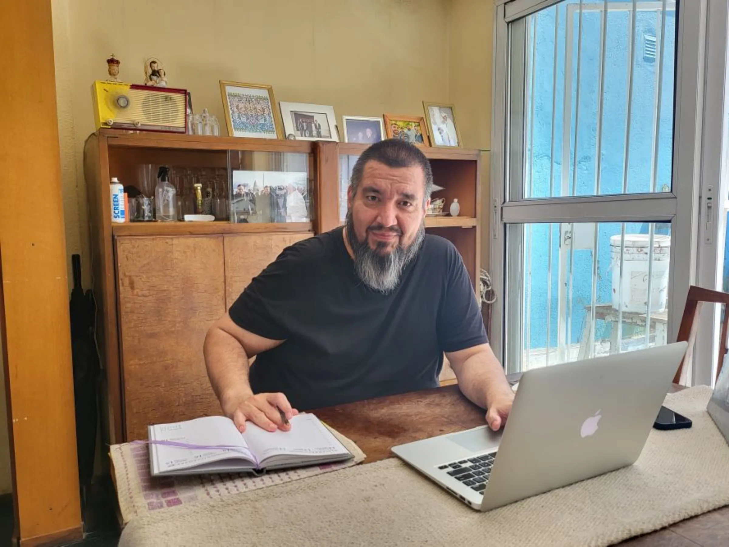 Fabián Baez, a parish priest who created a digital wallet for cryptocurrency to fund charitable causes, at his desk in Villa Urquiza, Buenos Aires, Argentina. December 5, 2022. Thomson Reuters Foundation/David Esteban Feliba