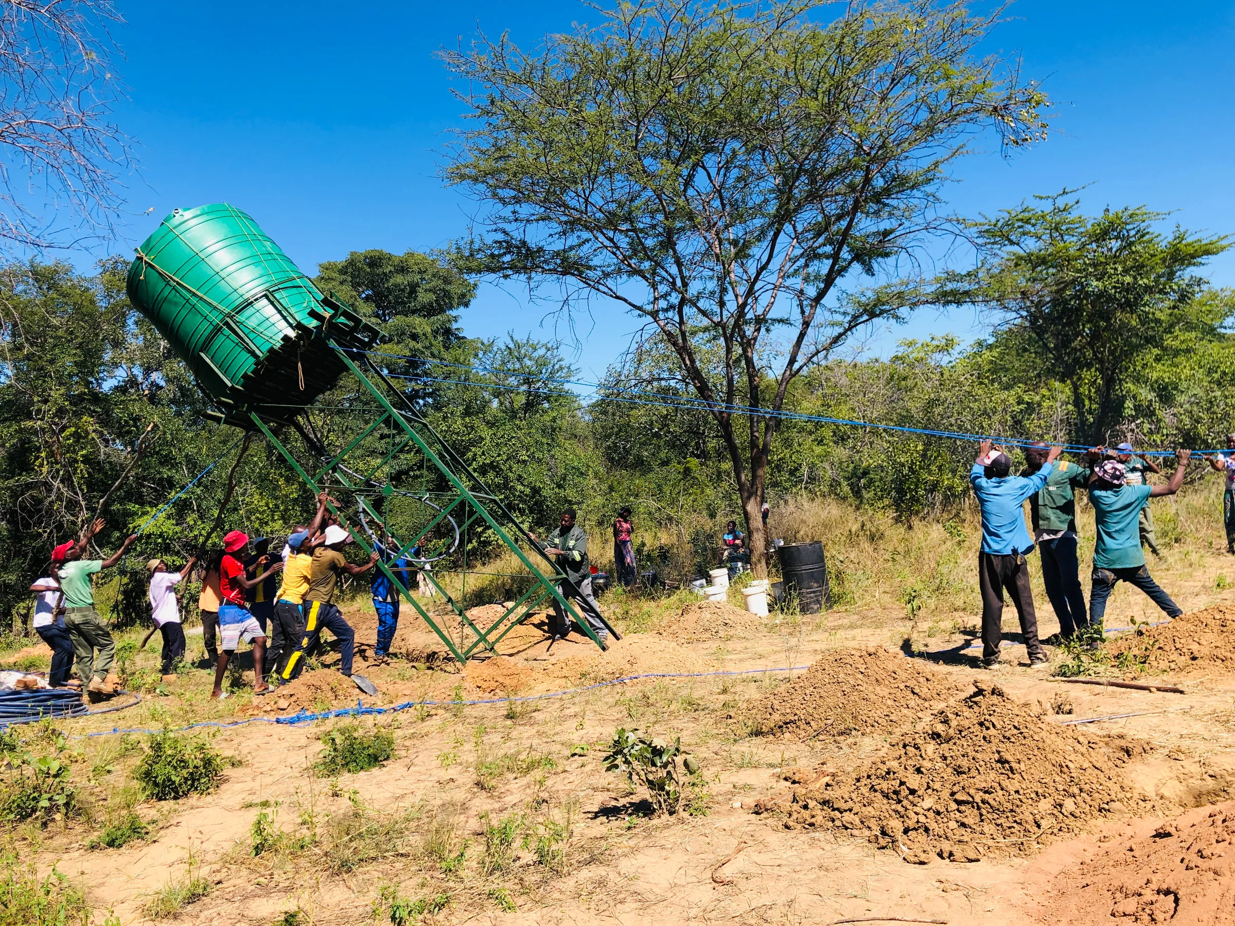 Suanyanga villagers put up a water tank for a borehole that will be powered by a solar system. The Ilaja Permaculture Garden and solar system was donated to the community through a collaboration between Soft Foot Alliance, Painted Dog Conservation, and Mother Africa. 7 May 2025. Lungelo Ndhlovu/Thomson Reuters Foundation.
