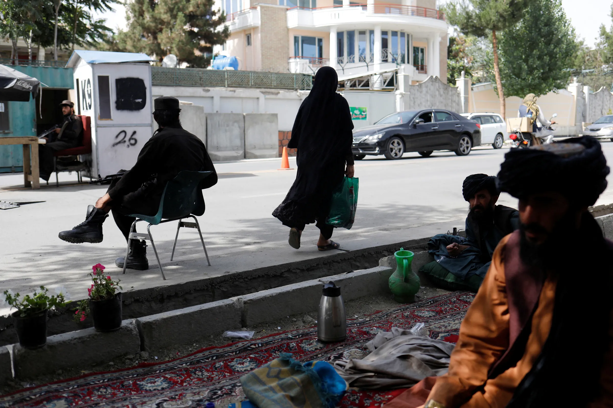 An Afghan woman walks among Taliban soldiers at a checkpoint in Kabul, Afghanistan, July 6, 2023. REUTERS/Ali Khara