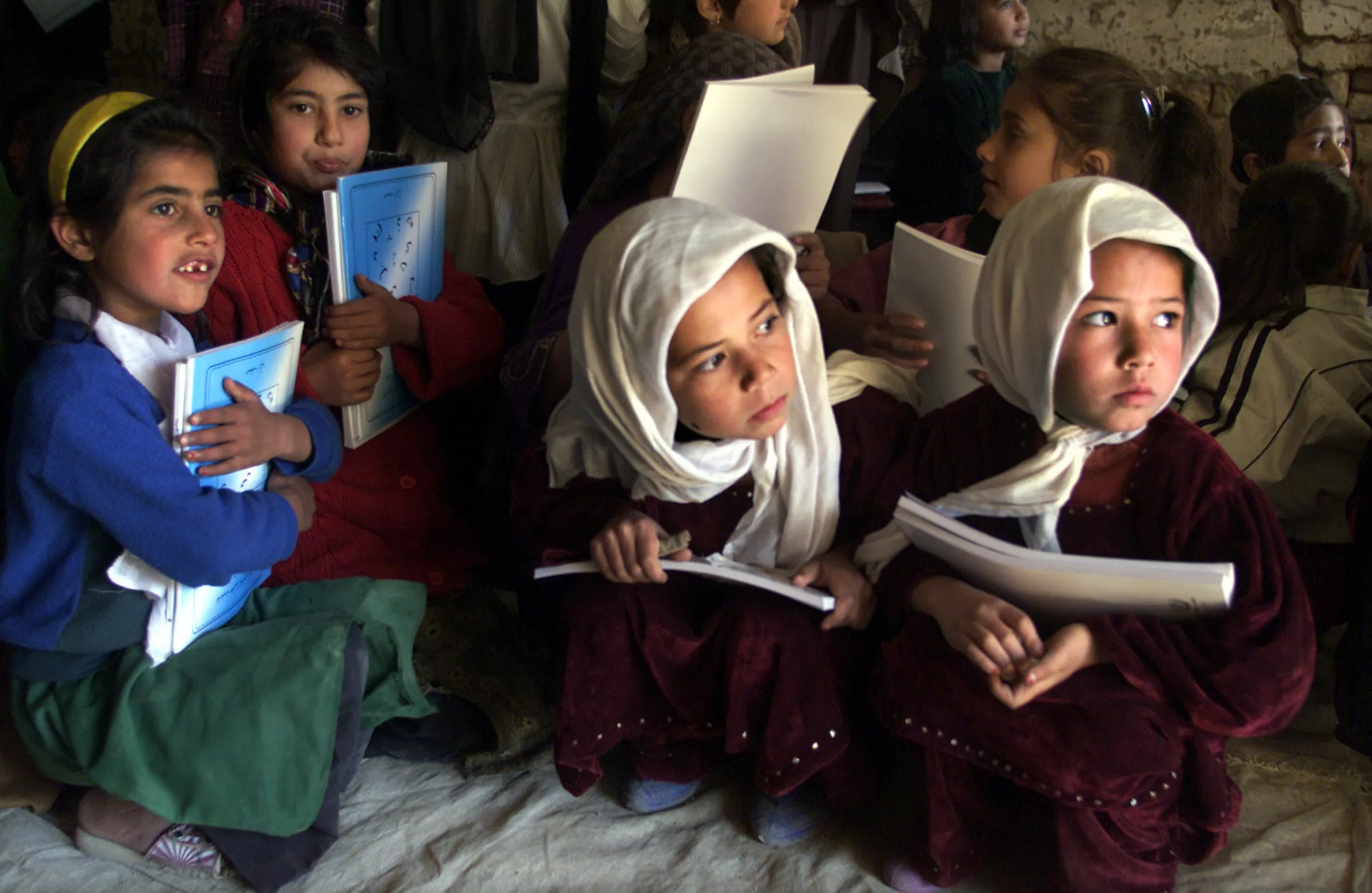 Afghan schoolgirls clutch UNICEF textbooks as school materials are distributed to students in Kabul, March 25, 2002. REUTERS/Jim Hollander