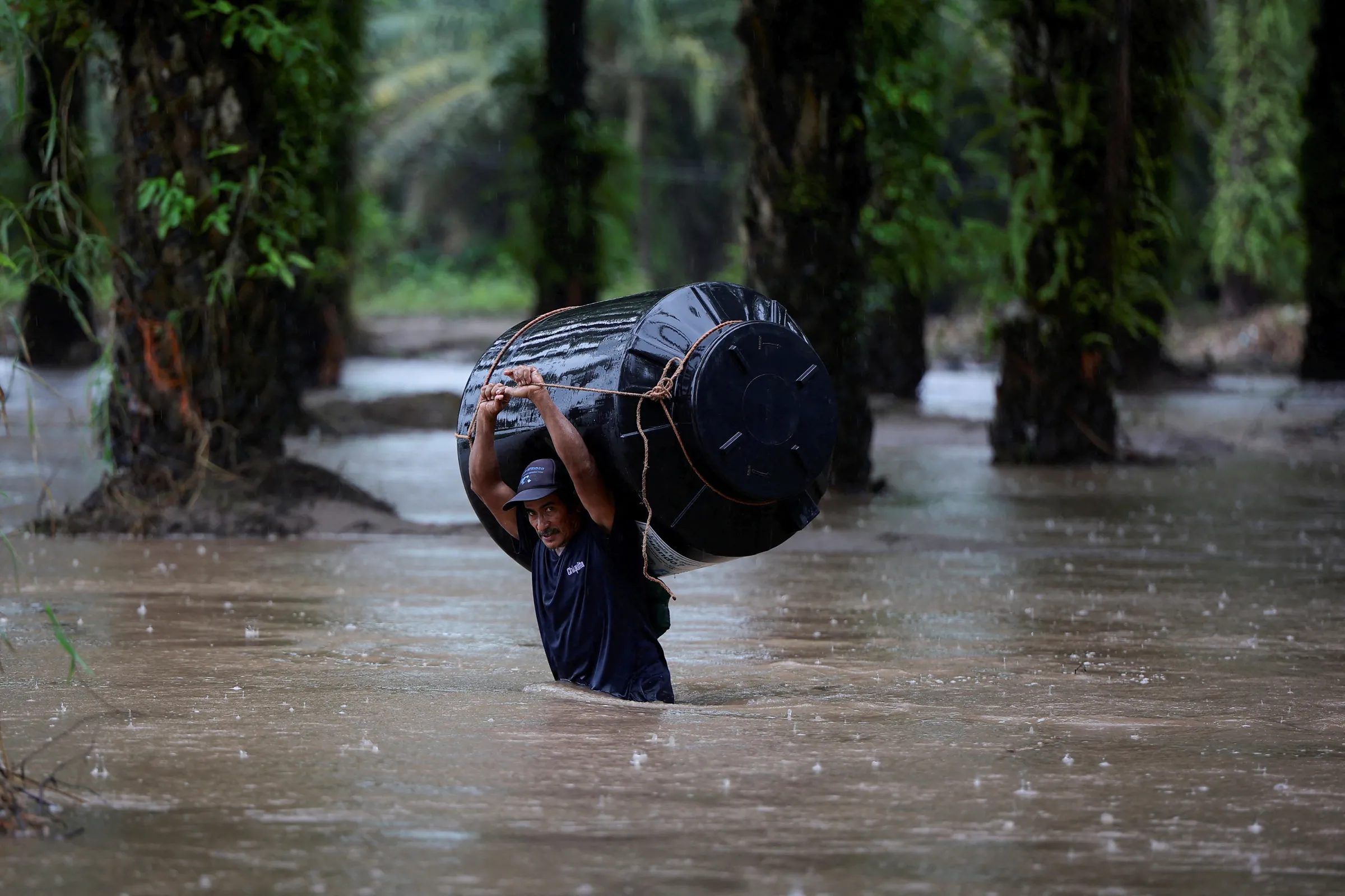 A man carries an empty water tank through a flooded area after the impact of the tropical storm Julia, in Progreso, Honduras October 9, 2022. REUTERS/Yoseph Amaya
