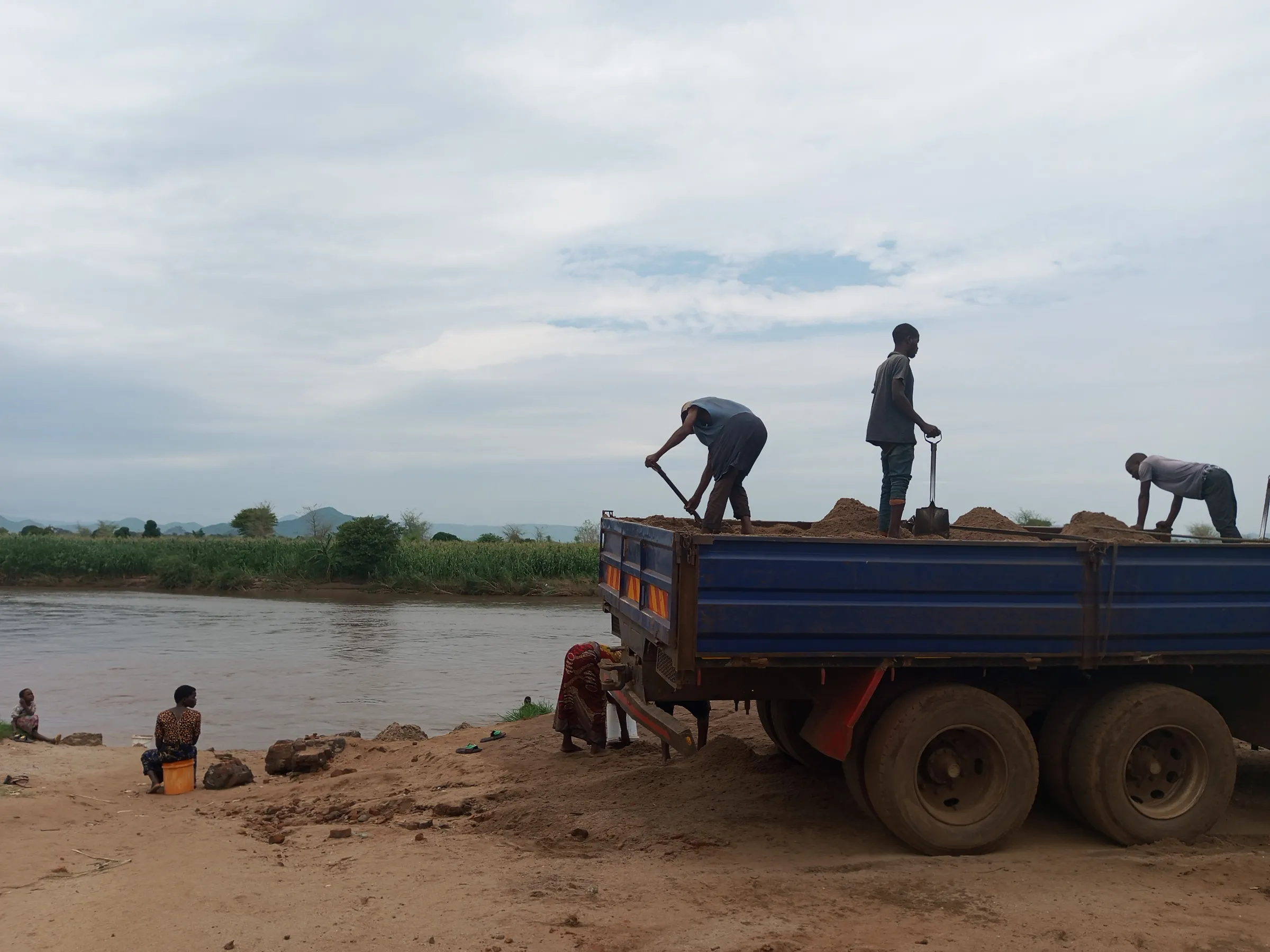 Young men load sand into a truck and will use the money they earn to buy maize to prepare meals for their families in Salima district near Lake Malawi, Malawi, Feb 28, 2025. Thomson Reuters Foundation/Charles Pensulo.