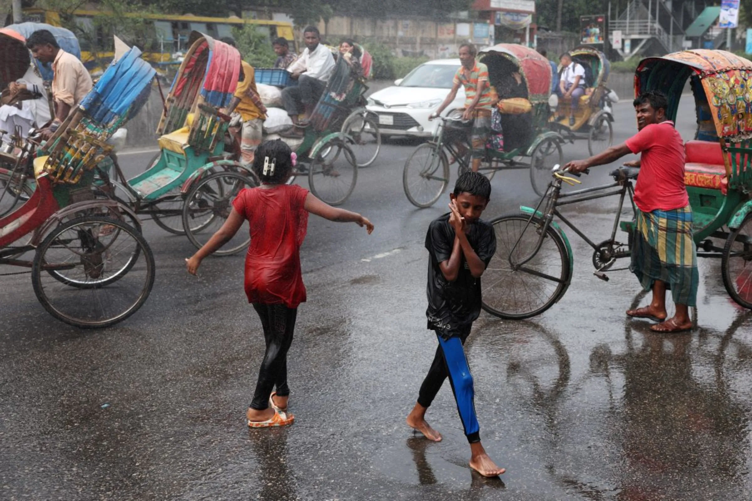 Children cool themselves in the water sprayed from a spray cannon during a countrywide heatwave in Dhaka, Bangladesh, April 28, 2024. REUTERS/Mohammad Ponir Hossain