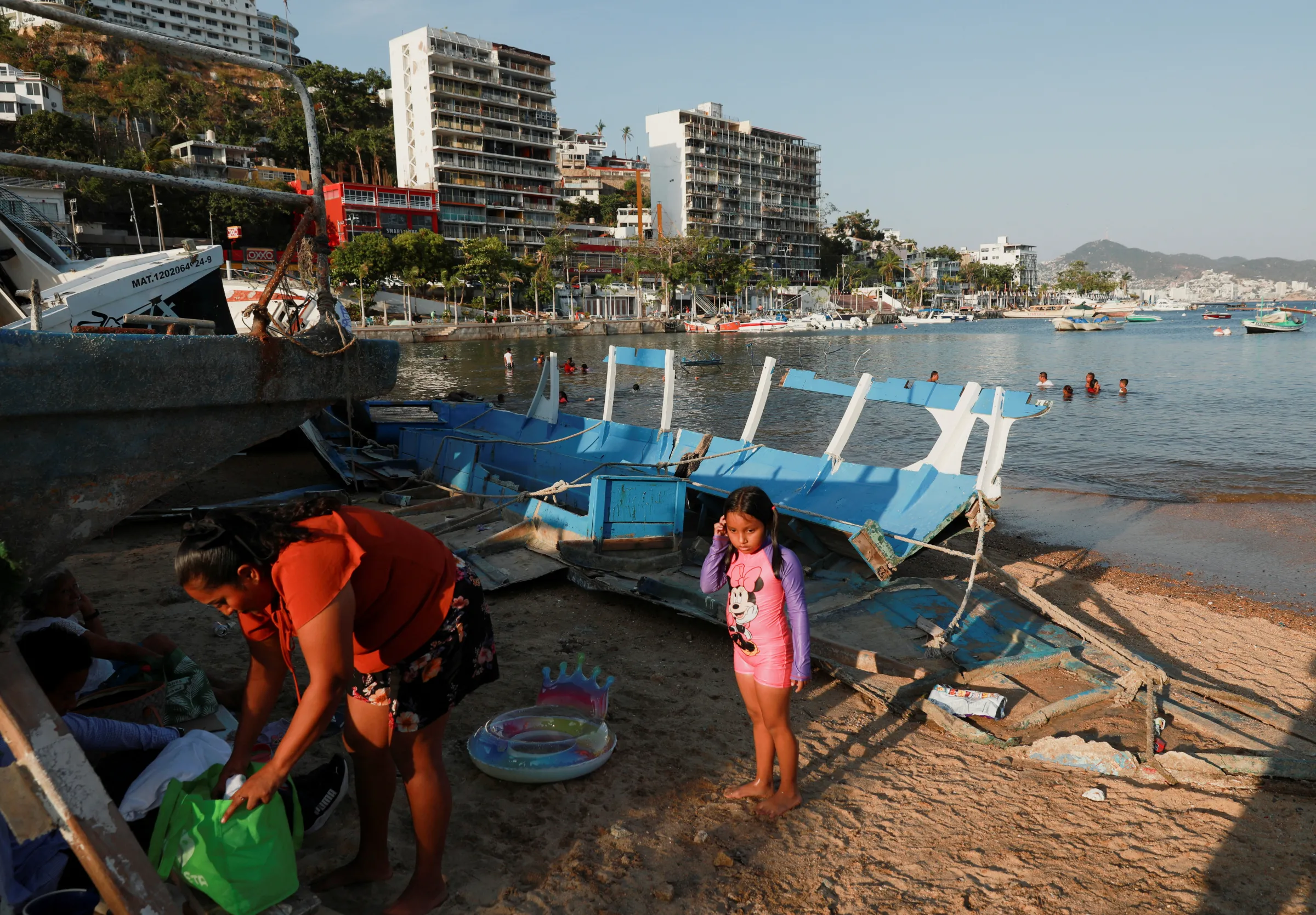 People stand near damaged boats caused by Hurricane Otis on October 25, 2023, in Acapulco, Guerrero state, Mexico, February 25, 2024. REUTERS/Henry Romero