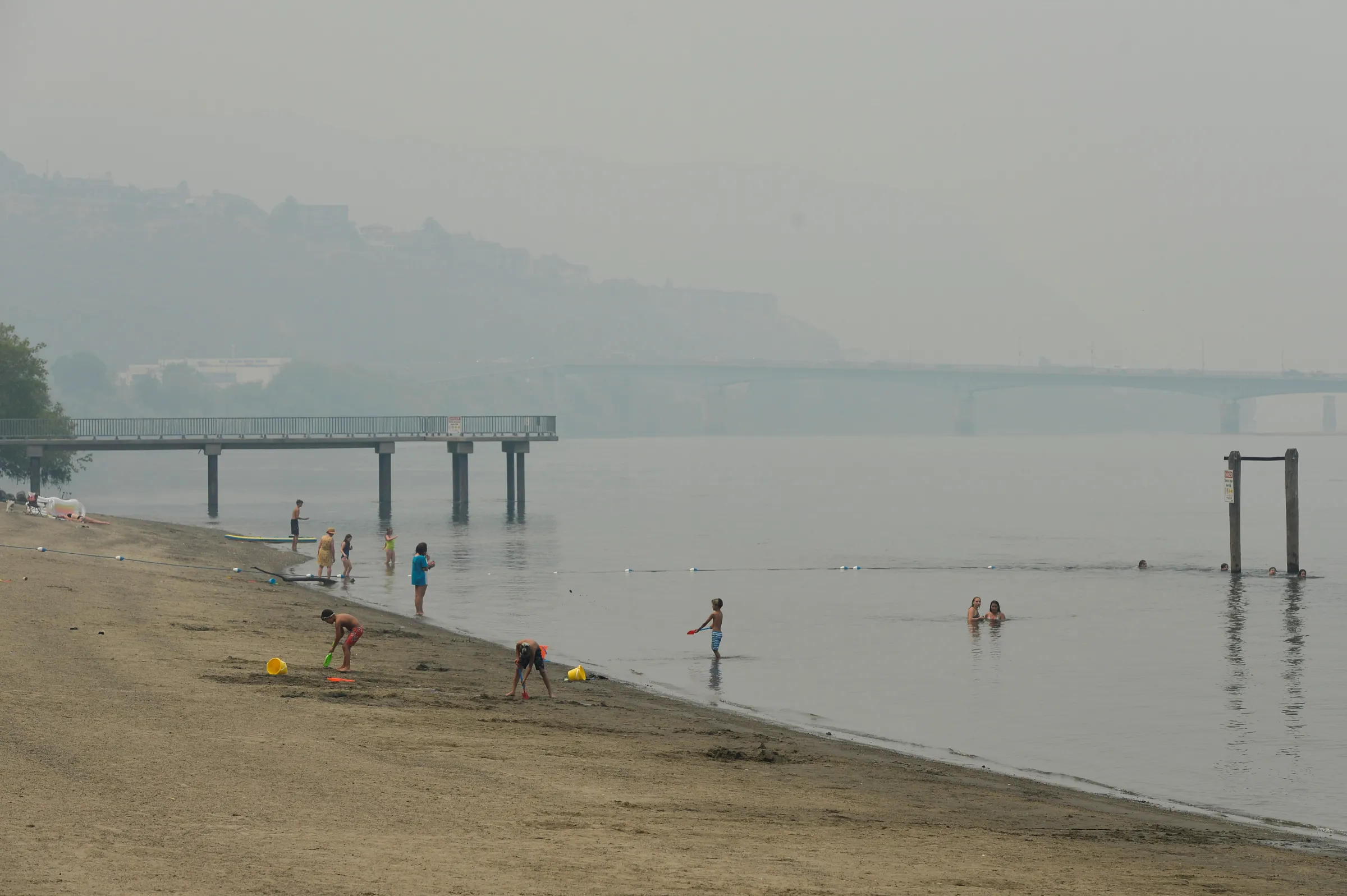 Swimmers cool off in the Thompson River under a blanket of smoke from nearby wildfires in Kamloops, British Columbia, Canada July 15, 2021. REUTERS/Jennifer Gauthier