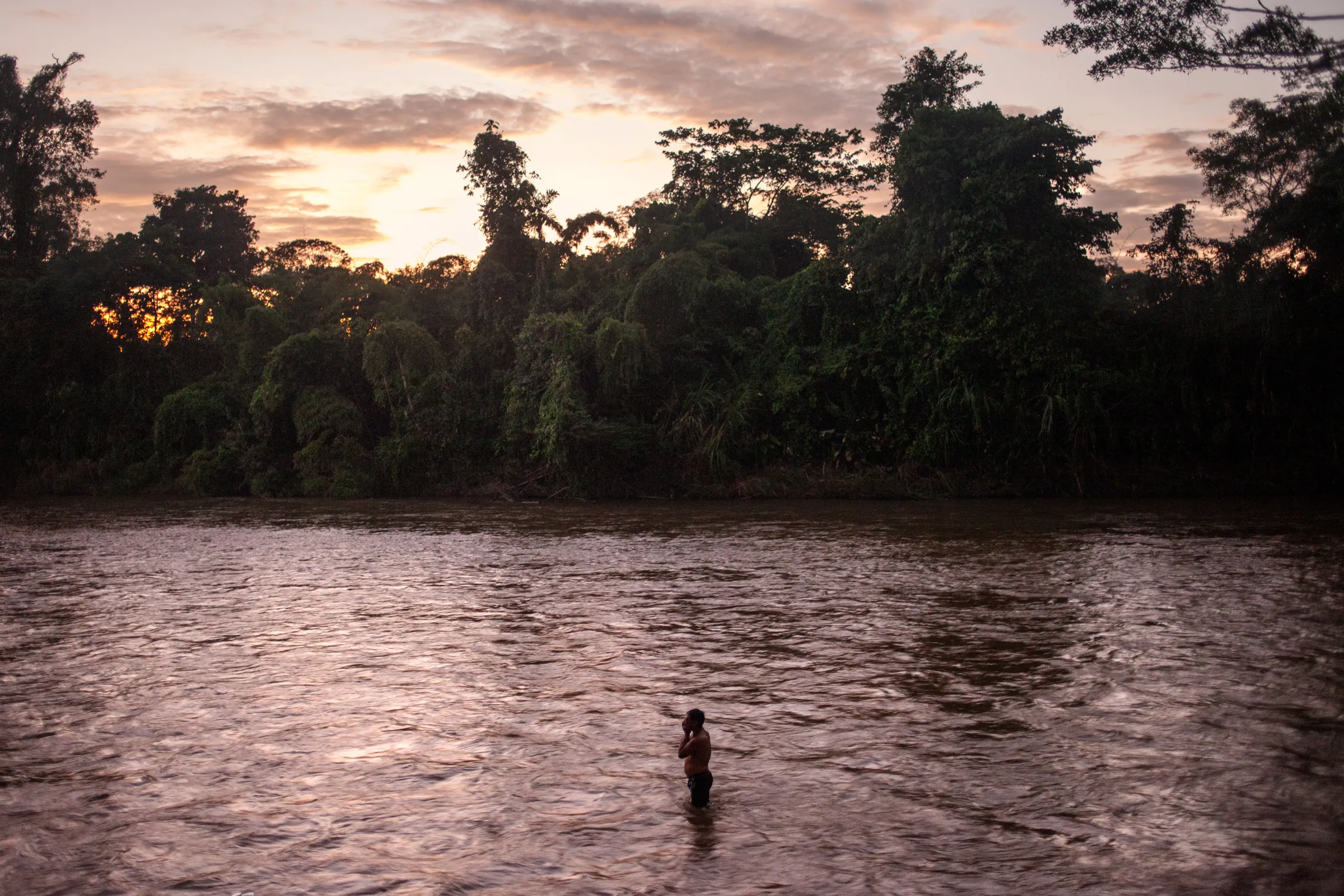 A man from the Waorani of Pastaza indigenous group bathes in the Curaray River at sunset in the Amazon province of Pastaza, Ecuador, on April 25, 2022. Thomson Reuters Foundation/Fabio Cuttica