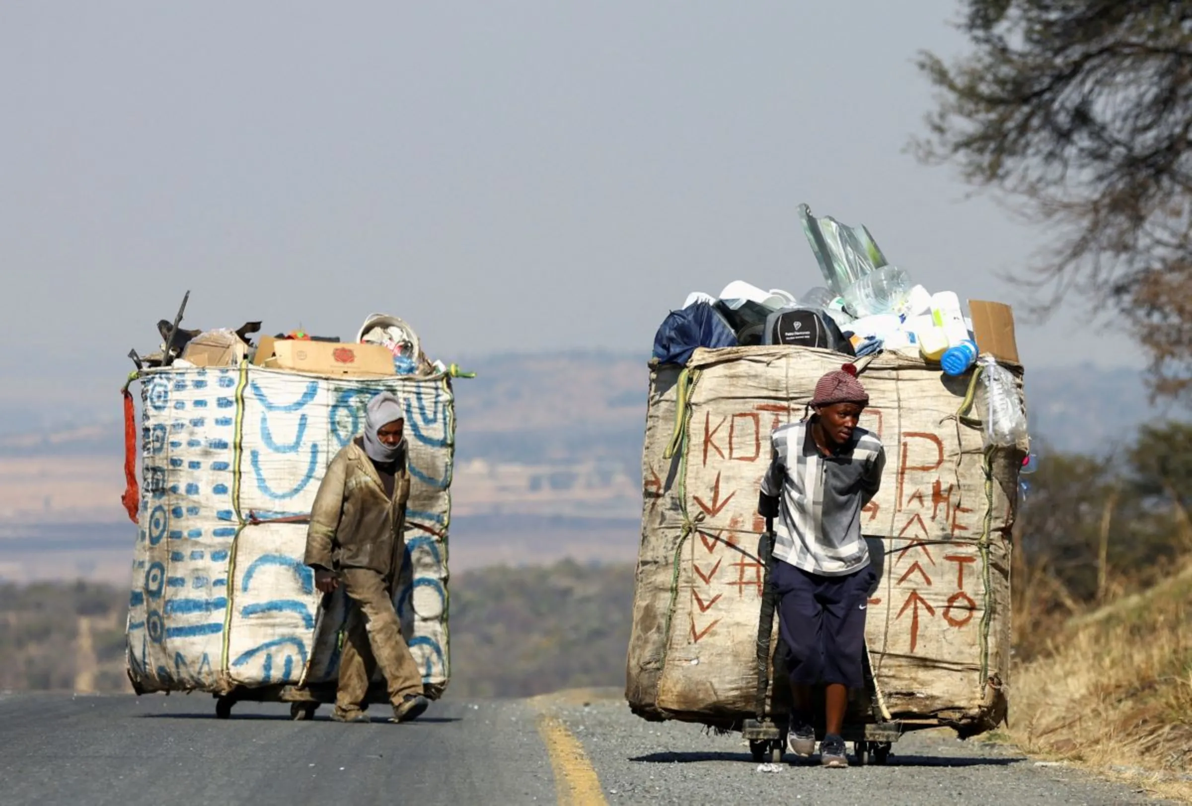 Steven Lesoona and Thabang Pule, waste pickers, pull trolleys loaded with recyclable materials, as they combat unemployment in Naturena, near Johannesburg, South Africa, July 3, 2023. REUTERS/Siphiwe Sibeko