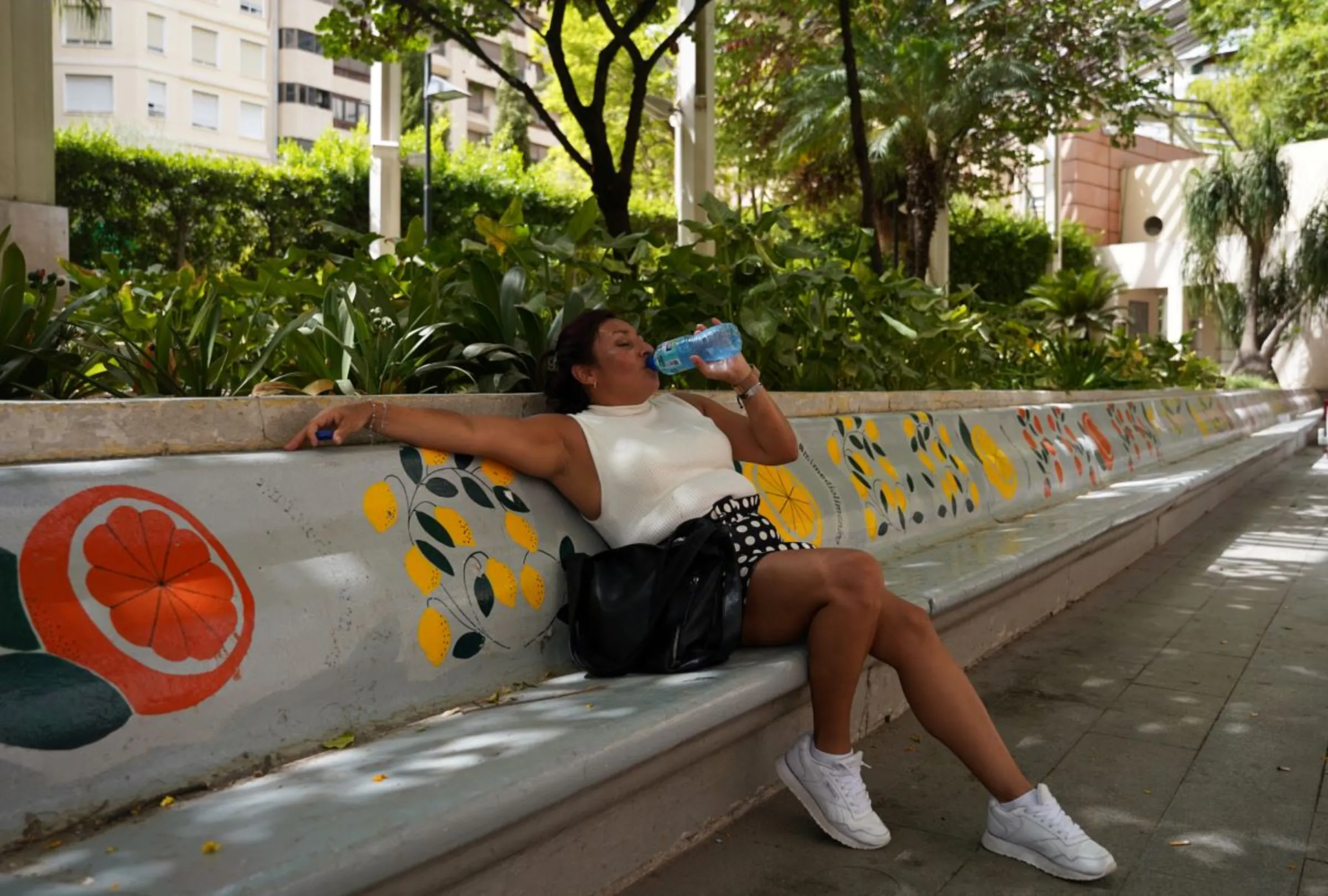 A woman sits as she drinks water amid the third heatwave of the summer, in downtown Murcia, Spain August 10, 2023