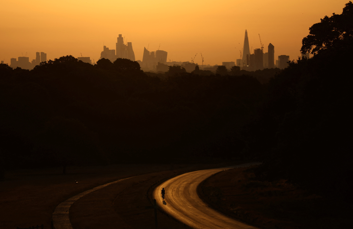 A cyclist rides through Richmond Park at sunrise during a heatwave in London