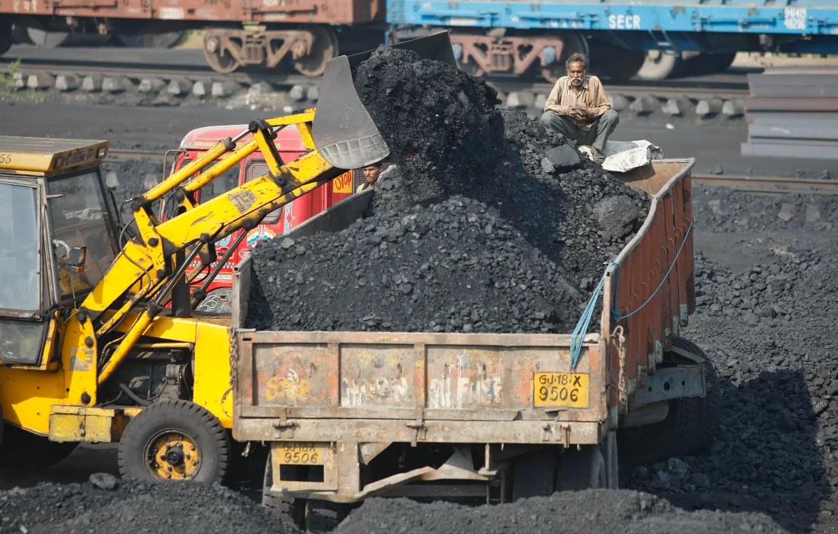 A worker sits on a truck being loaded with coal at a railway coal yard on the outskirts of the western Indian city of Ahmedabad