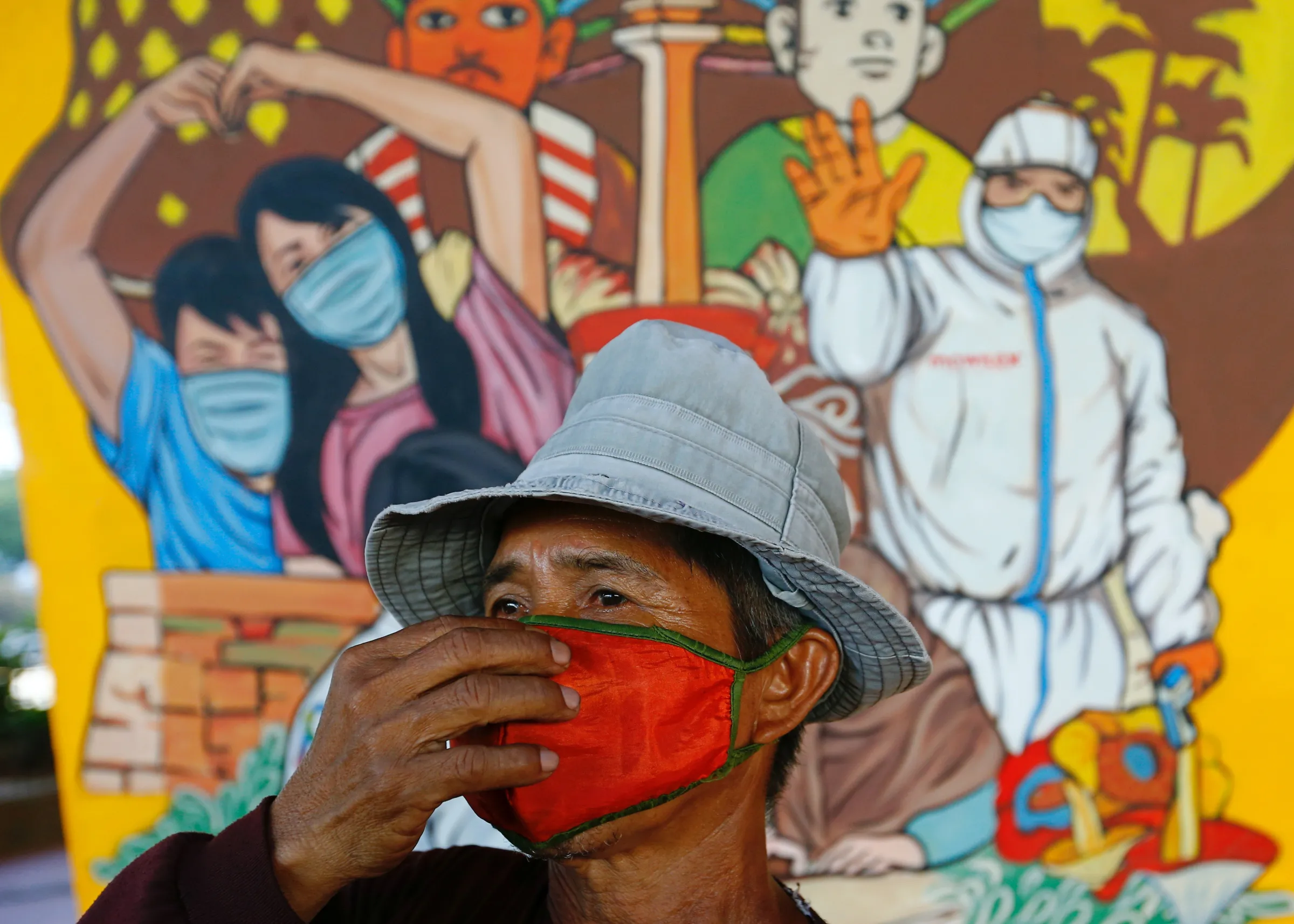 A man wearing a protective face mask walks near a mural promoting awareness of the coronavirus disease (COVID-19) outbreak in Jakarta, Indonesia, December 1, 2020. REUTERS/Ajeng Dinar Ulfiana