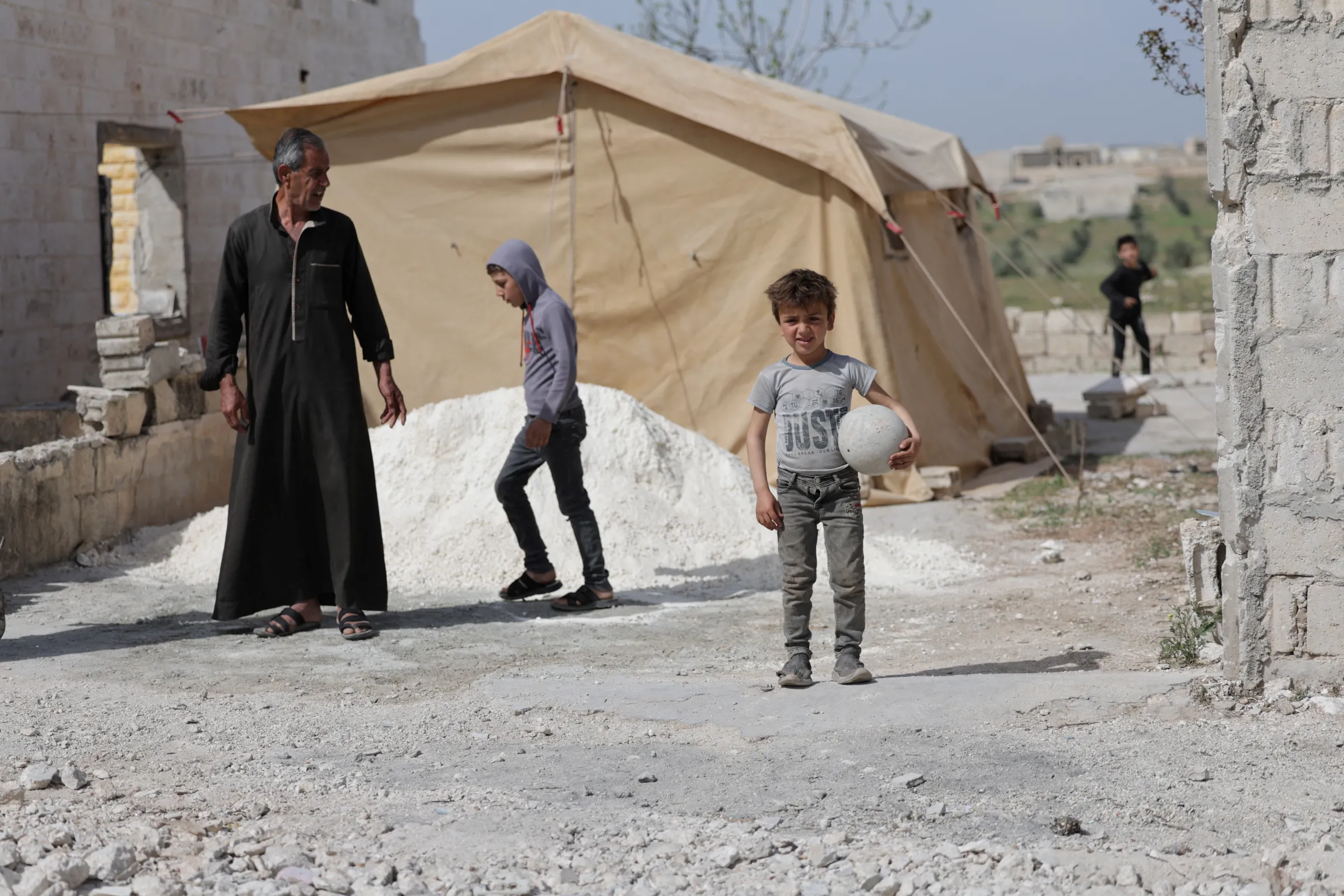 Hassan al-Ahmad, 65, stands next to a tent installed next to his damaged house in Idlib, Syria March 28, 2025. REUTERS/Khalil Ashawi