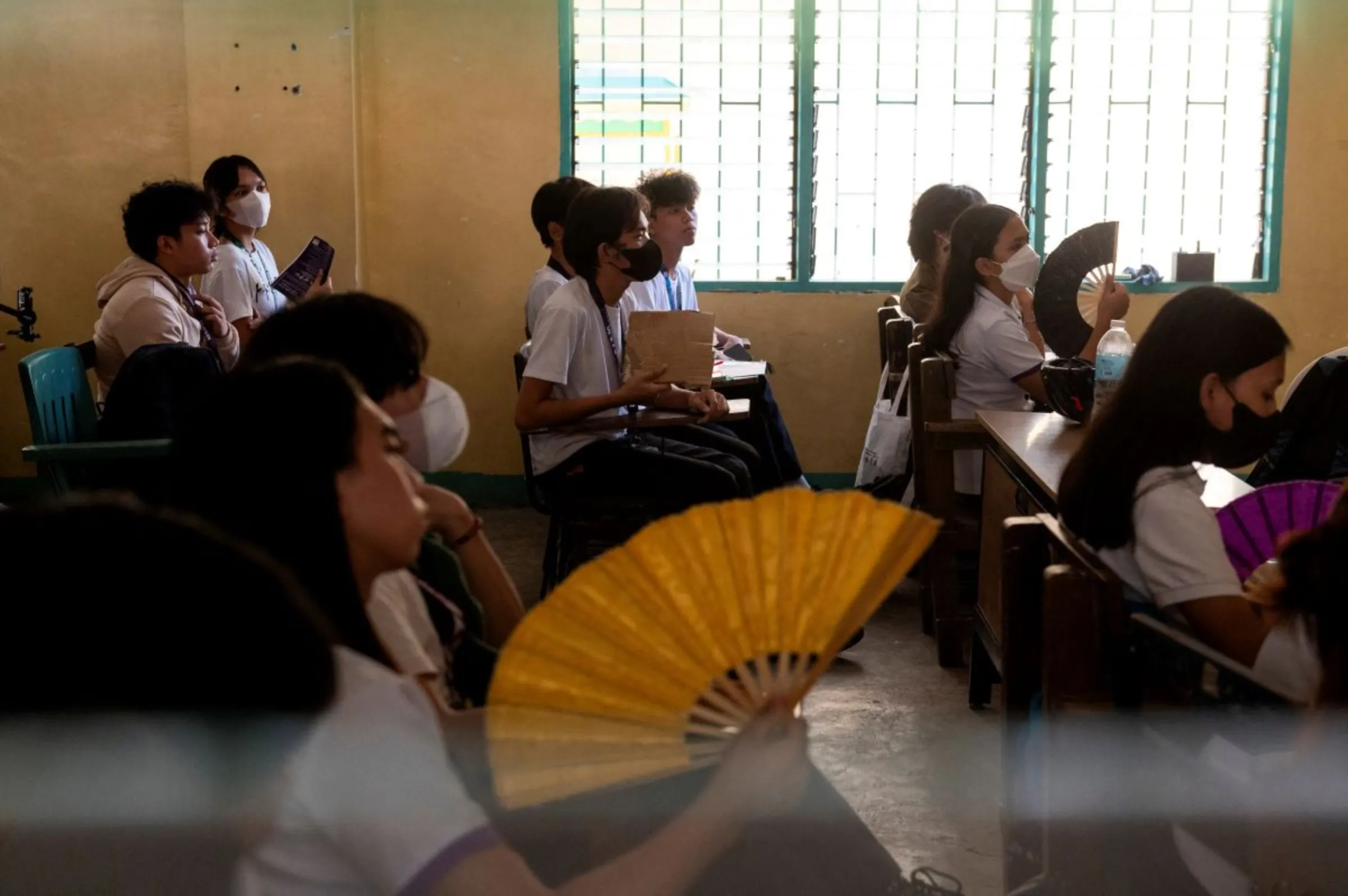 Students use hand fans and makeshift fans as they attend a class at the Commonwealth High School, in Quezon City, Metro Manila, Philippines, April 18, 2024. REUTERS/Lisa Marie David