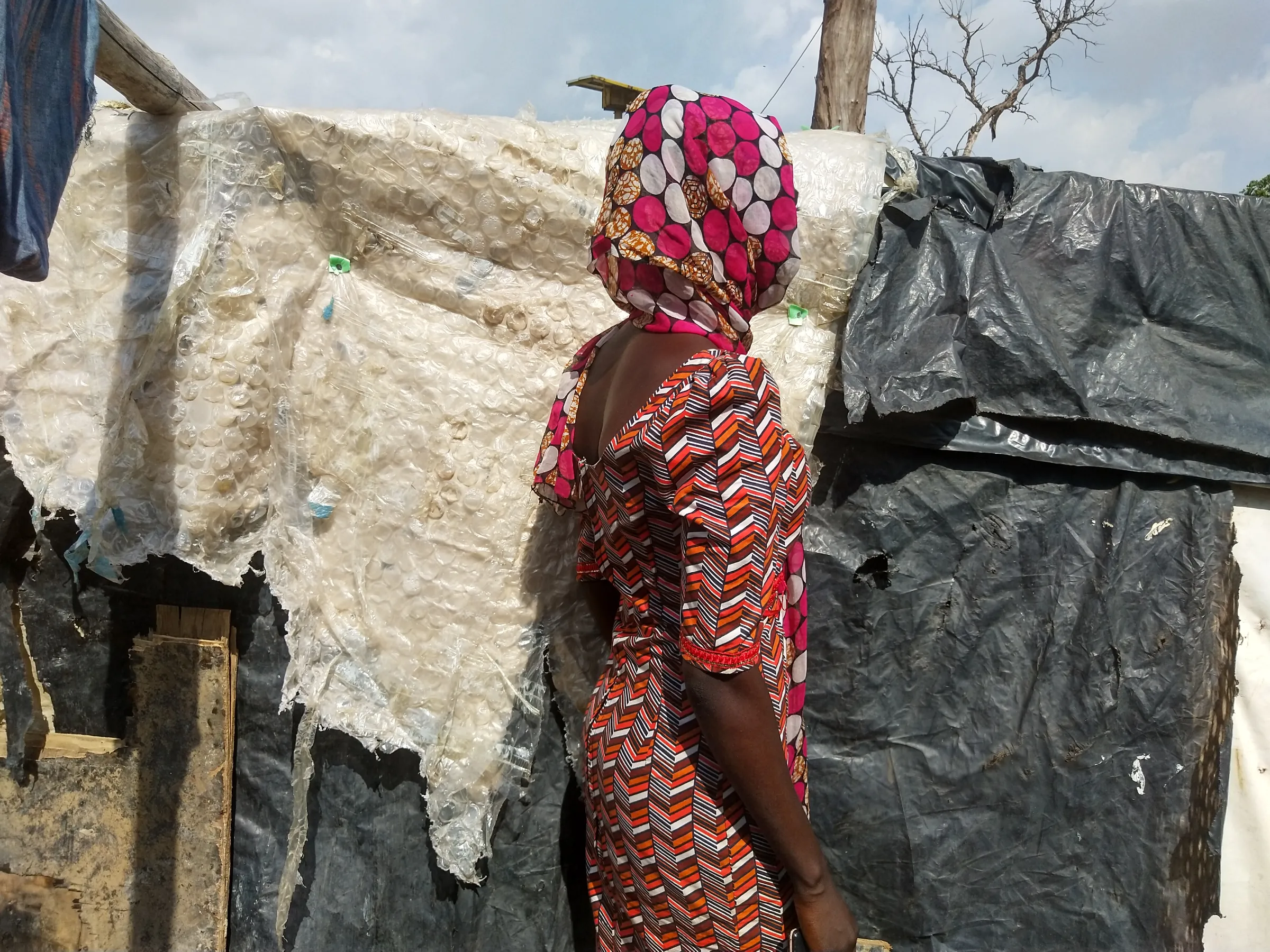 A woman wearing a headscarf turns her face from the camera