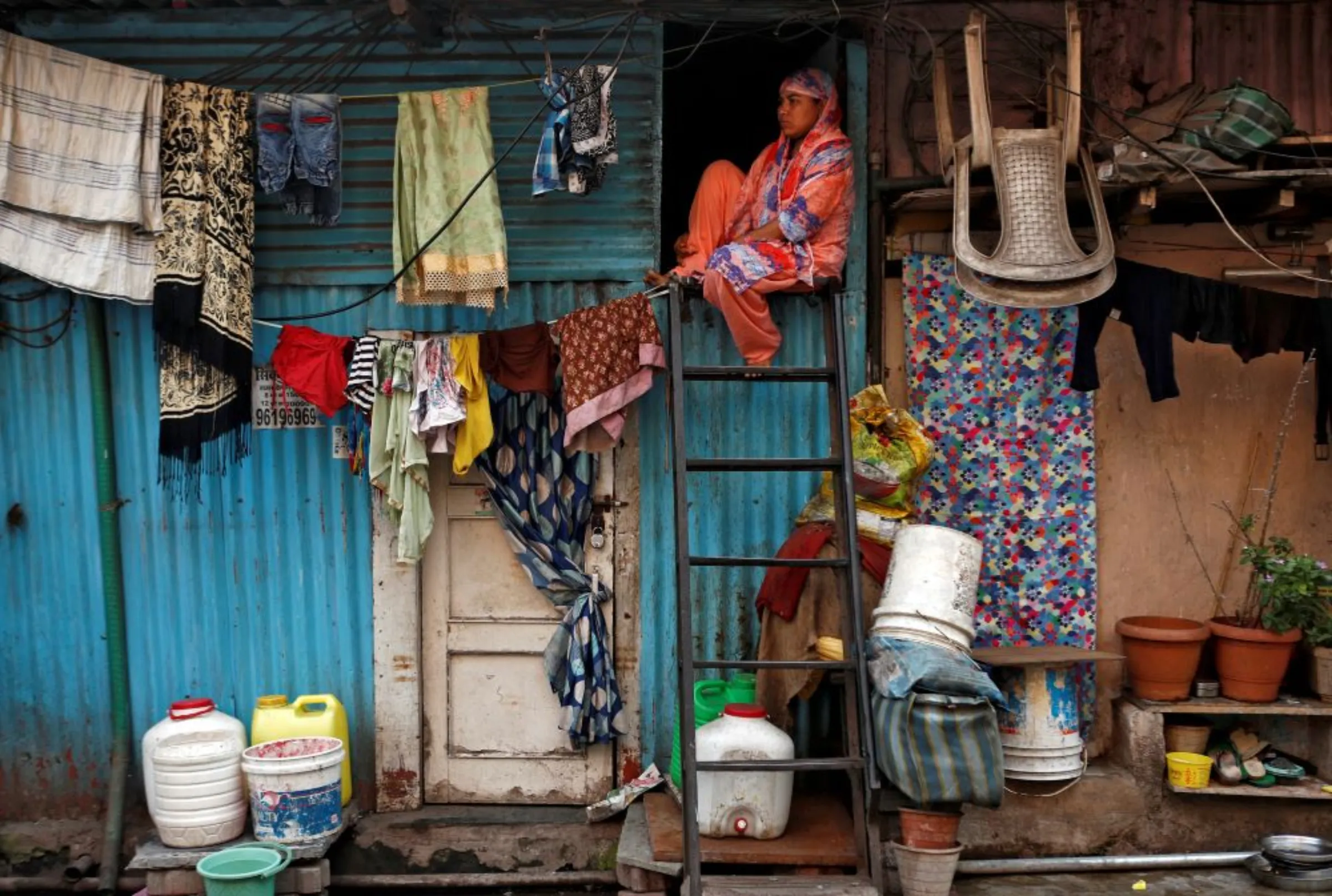 A woman sits on a ladder installed outside her house, in Dharavi, one of Asia's largest slums, in Mumbai, India, April 13, 2020