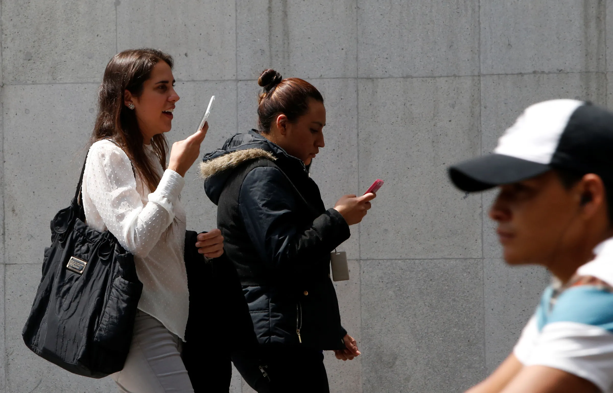 Women use their mobile phones while walking in Mexico City, Mexico July 5, 2017. REUTERS/Carlos Jasso