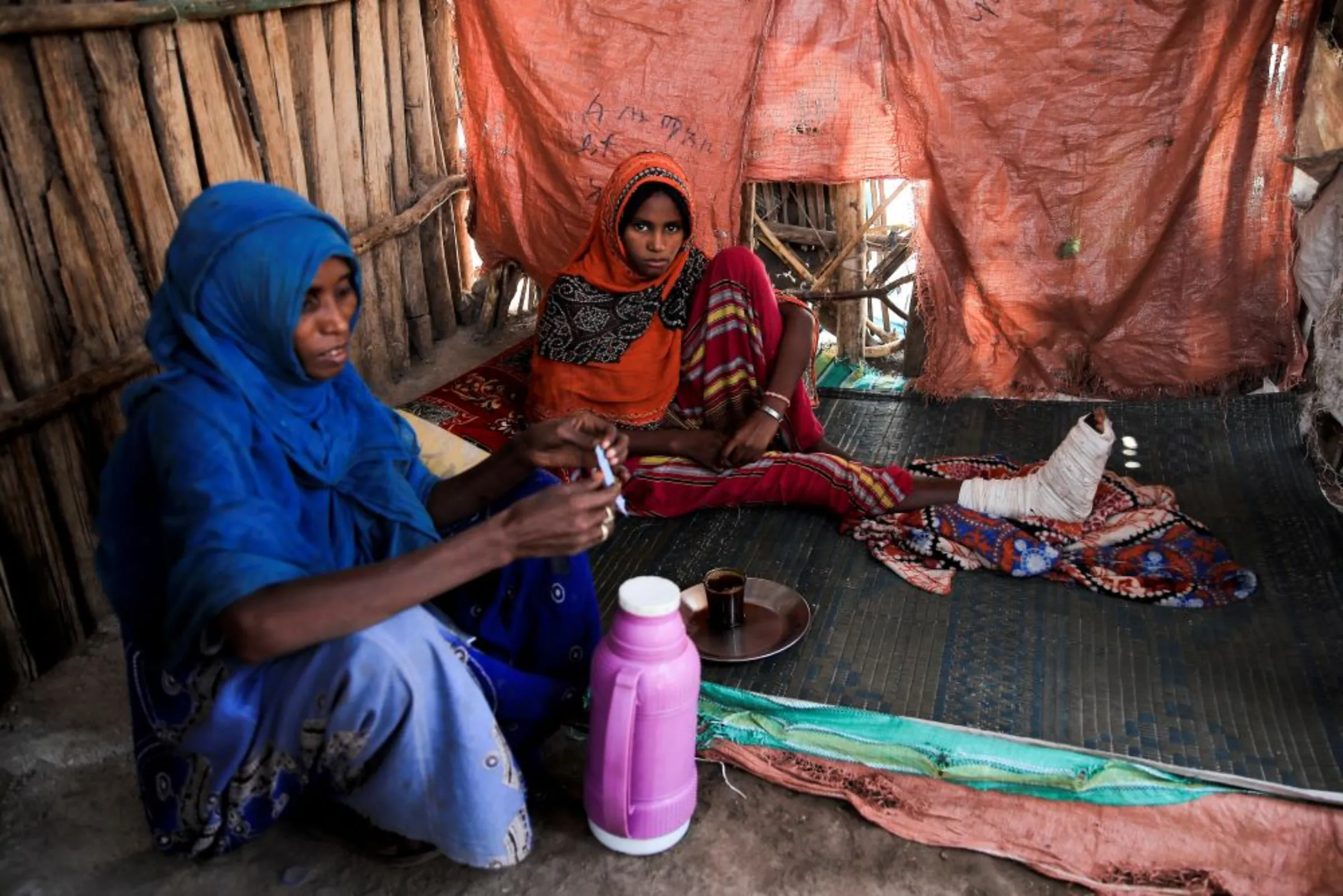 A girl sits at home with her mother after sustaining injuries to her right leg from explosives in Kasagita town, Afar region, Ethiopia, February 25, 2022