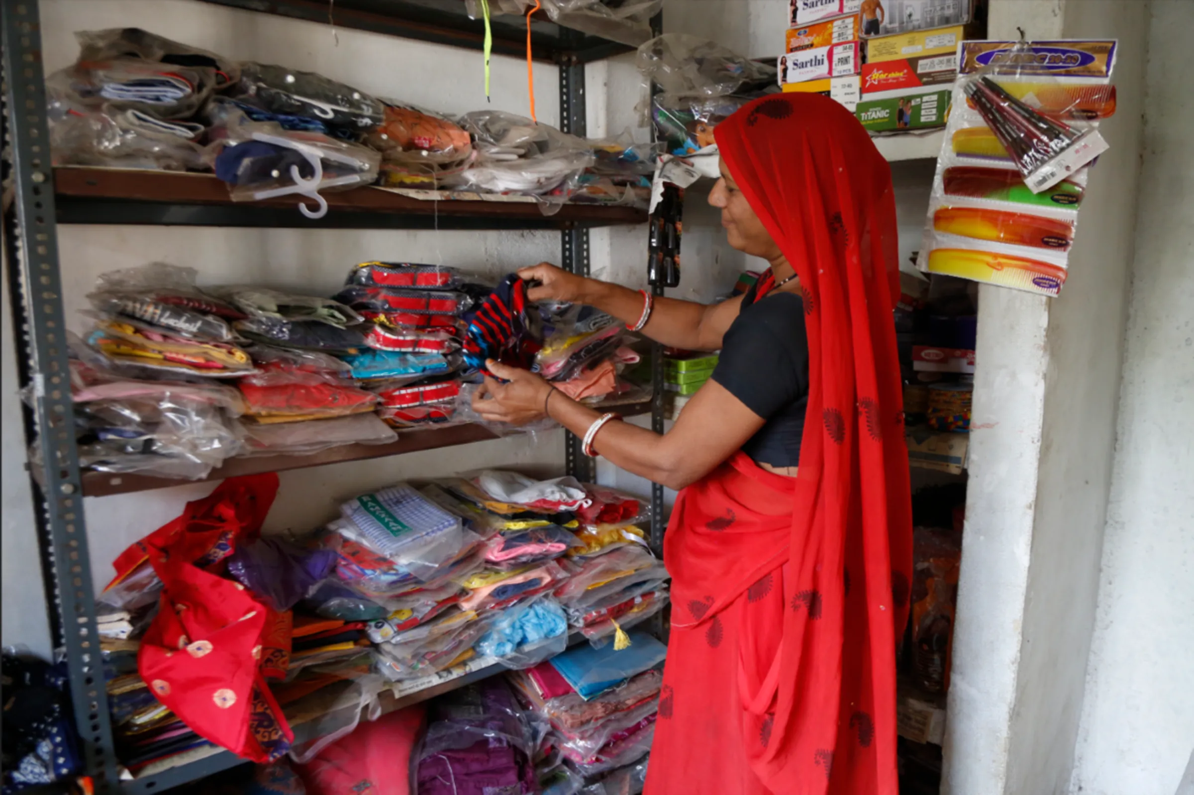 Chandrawati Rajpoot takes out a shirt from a plastic bag at her shop, which she opened with the help of a microloan, in Narela, Madhya Pradesh, November 10, 2022