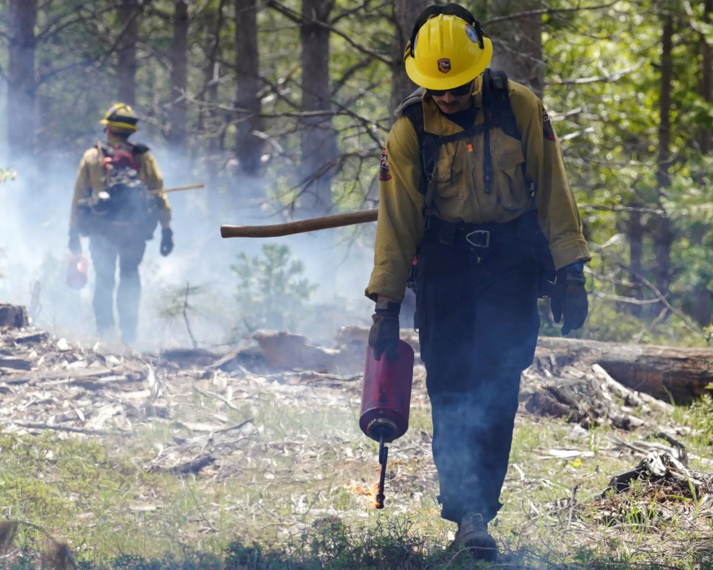 CAL FIRE firefighters from Tuolumne County's Baseline Fire Center use drip torches to light a prescribed burn, designed to help control potential wildfires, in the Stanislaus National Forest near Yosemite, California, U.S. May 8, 2023