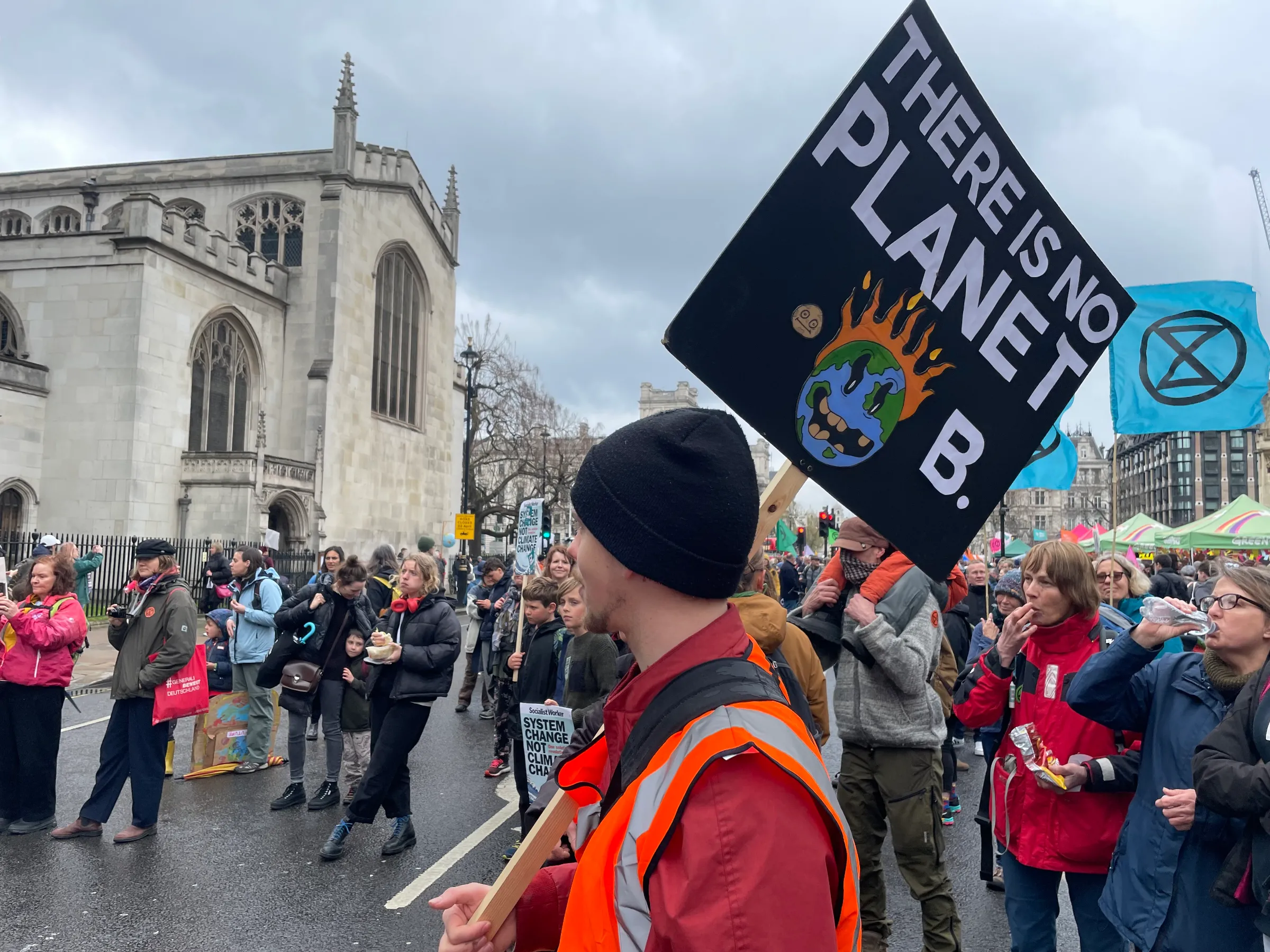 A climate change activist carrying a placard reading, “There is no Planet B” listens to speeches at “The Big One”, a protest organised by Extinction Rebellion outside Parliament in London on April 21, 2023. Thomson Reuters Foundation/Laurie Goering